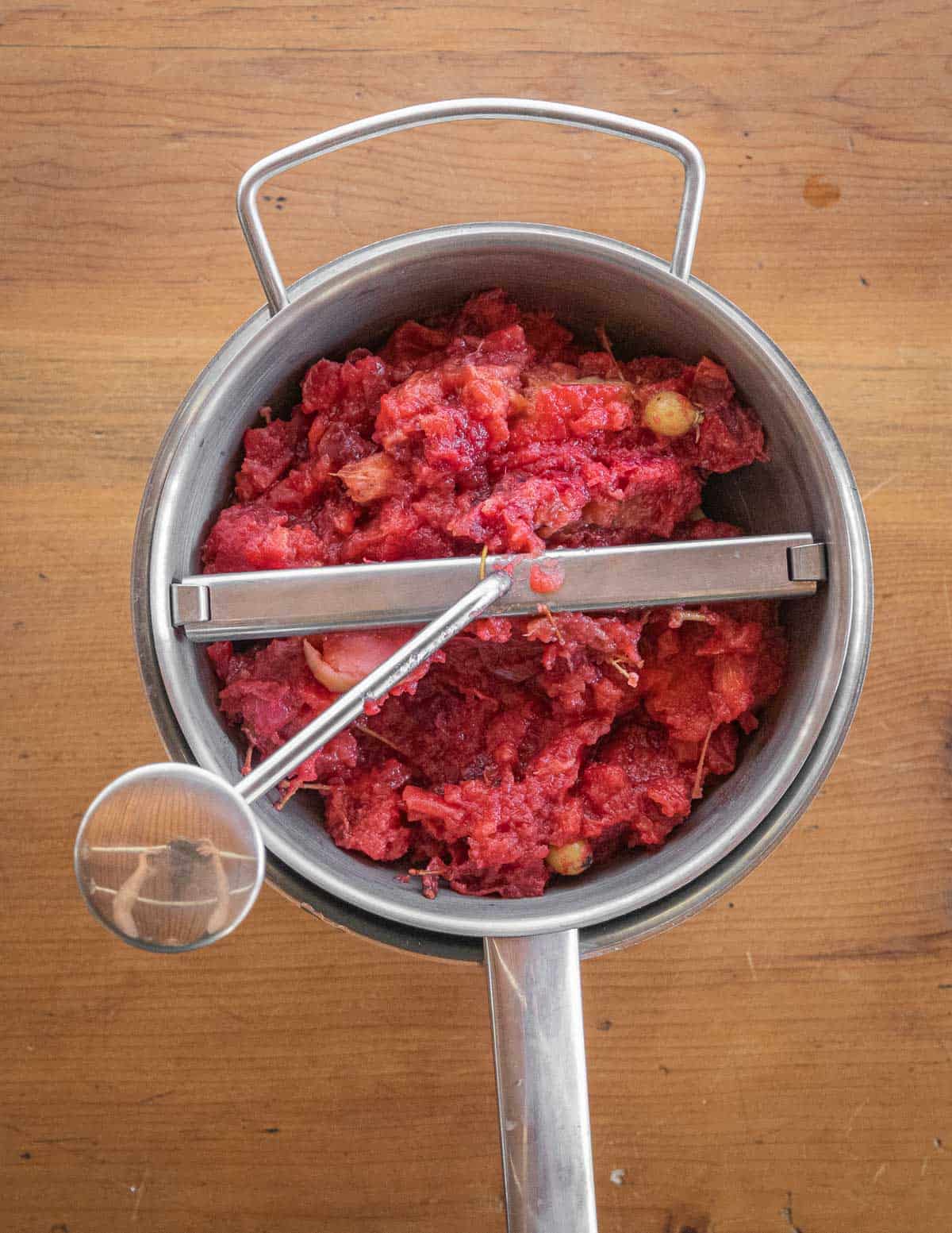 Putting cooked red crab apples through a food mill. 