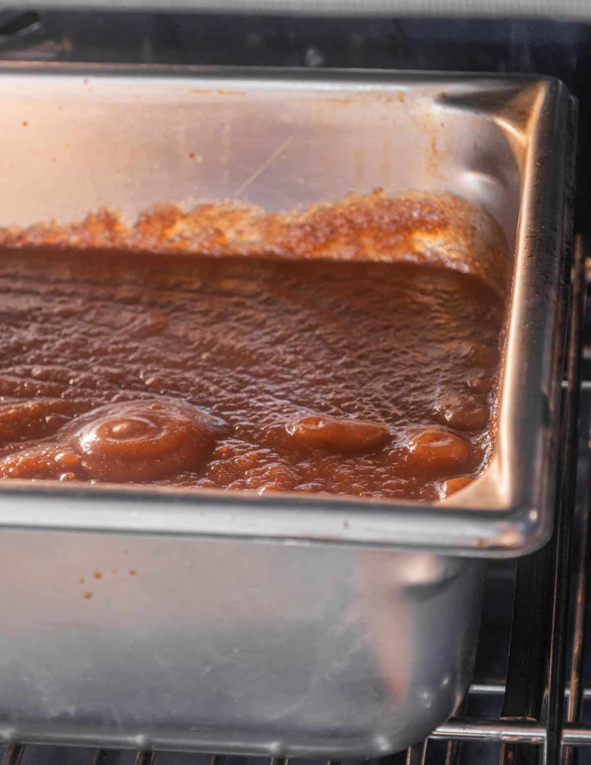 A tray of bubbling apple butter baking in the oven. 