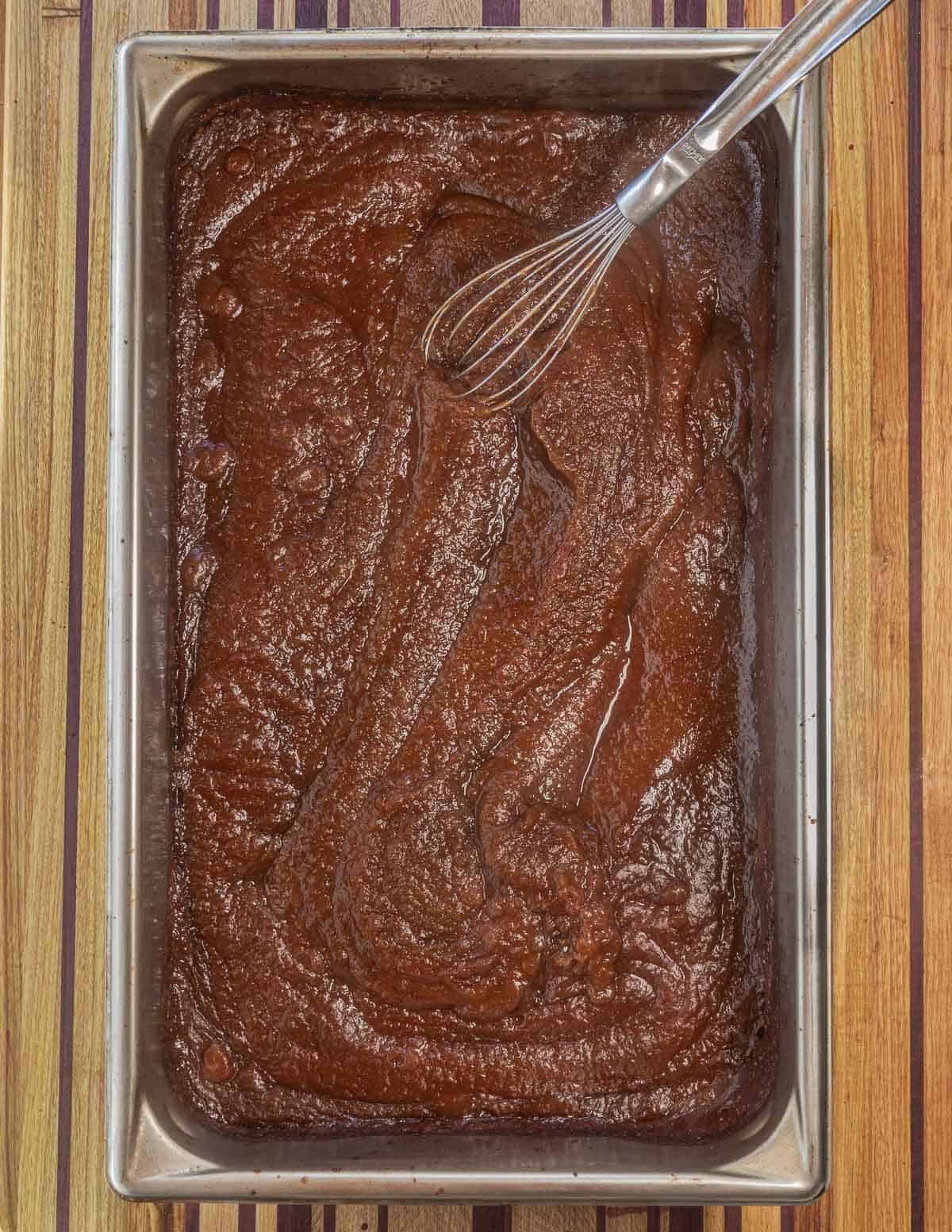 Dark brown apple butter being whisked after baking. 