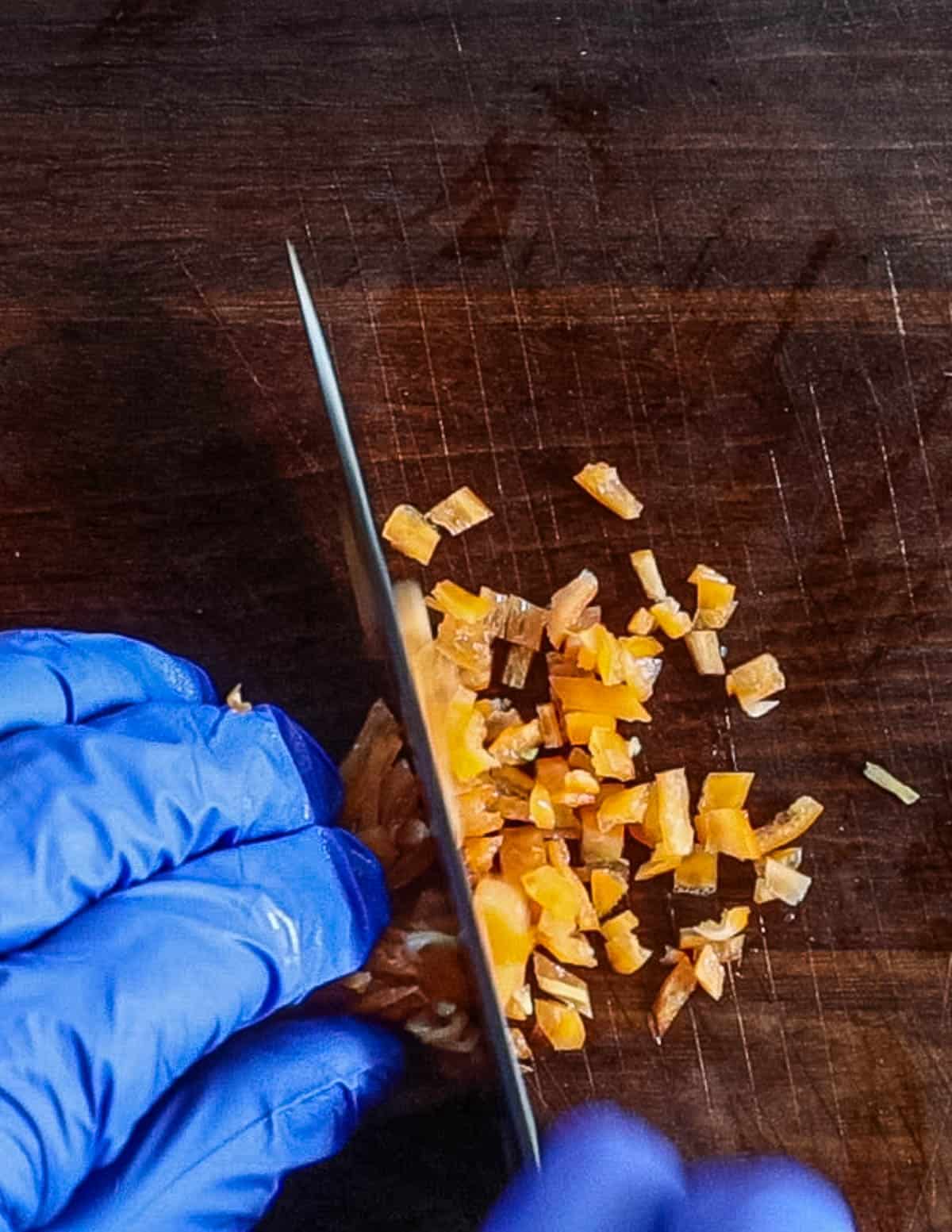 Finely chopping habanero hot peppers. 