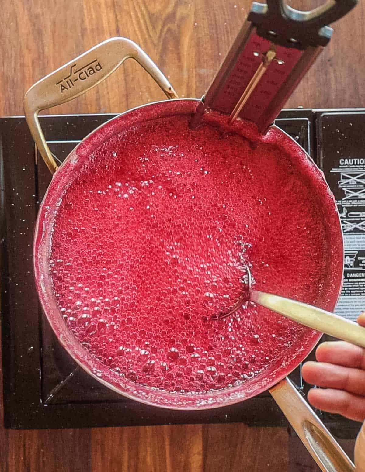 Boiling crab apple jelly in a pot with a candy thermometer. 