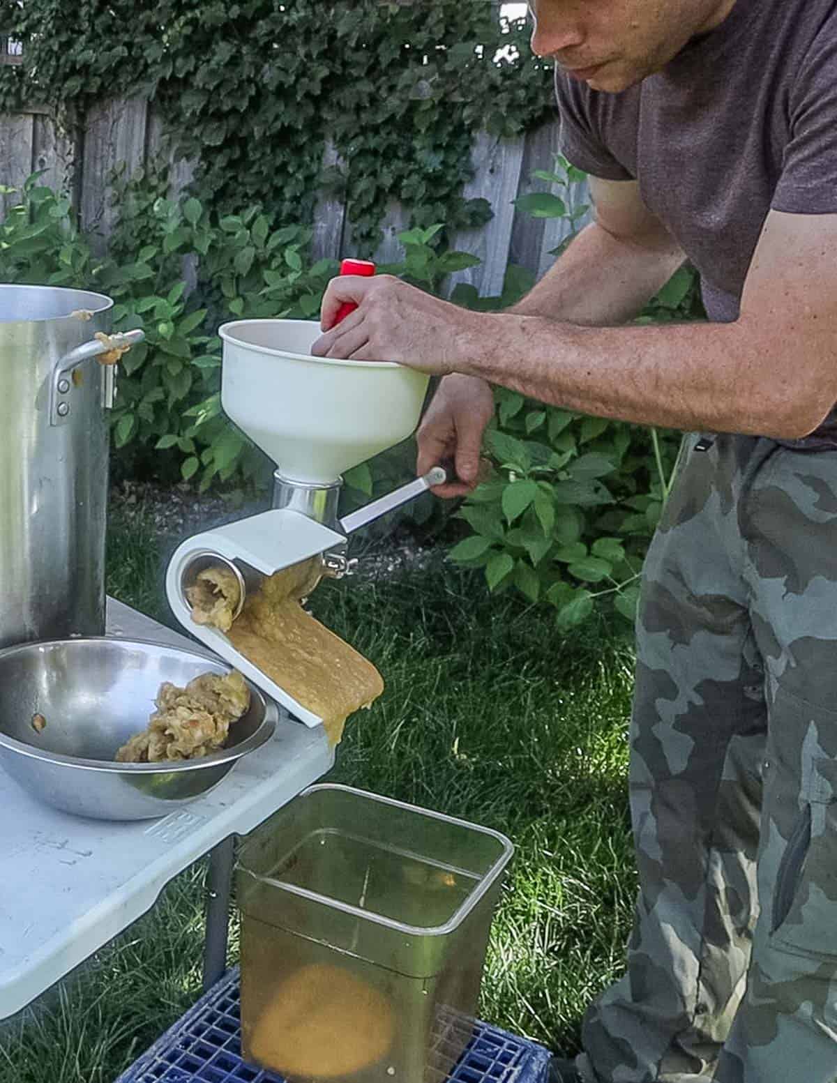 Passing apples through an apple sauce maker outside.