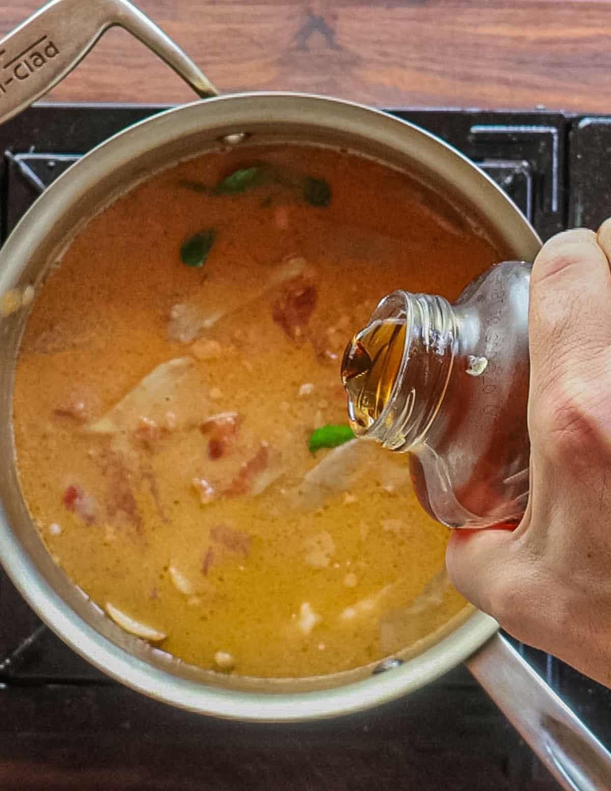 Adding maple syrup or sugar to a pot of Thai soup. 