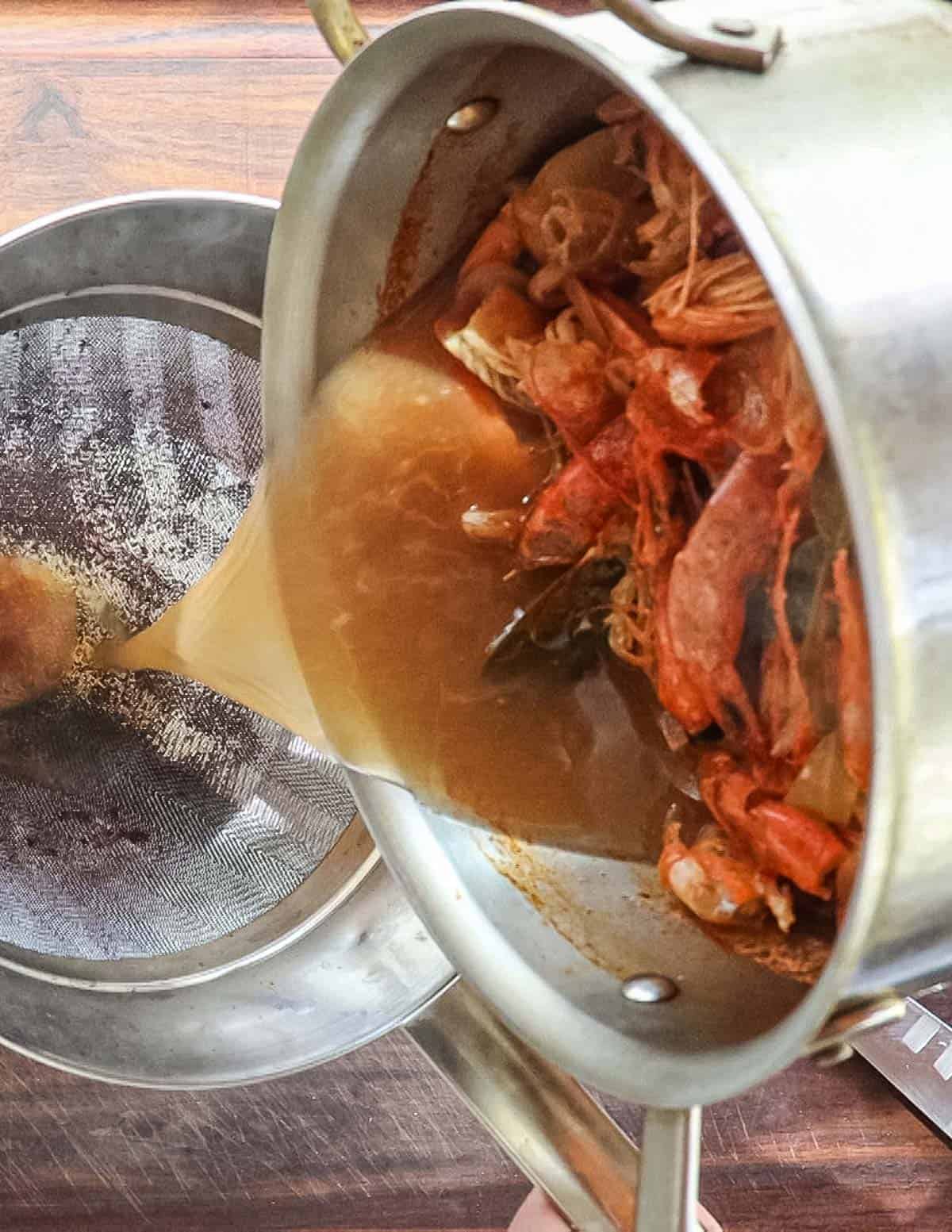 Straining shrimp stock through a chinois strainer. 