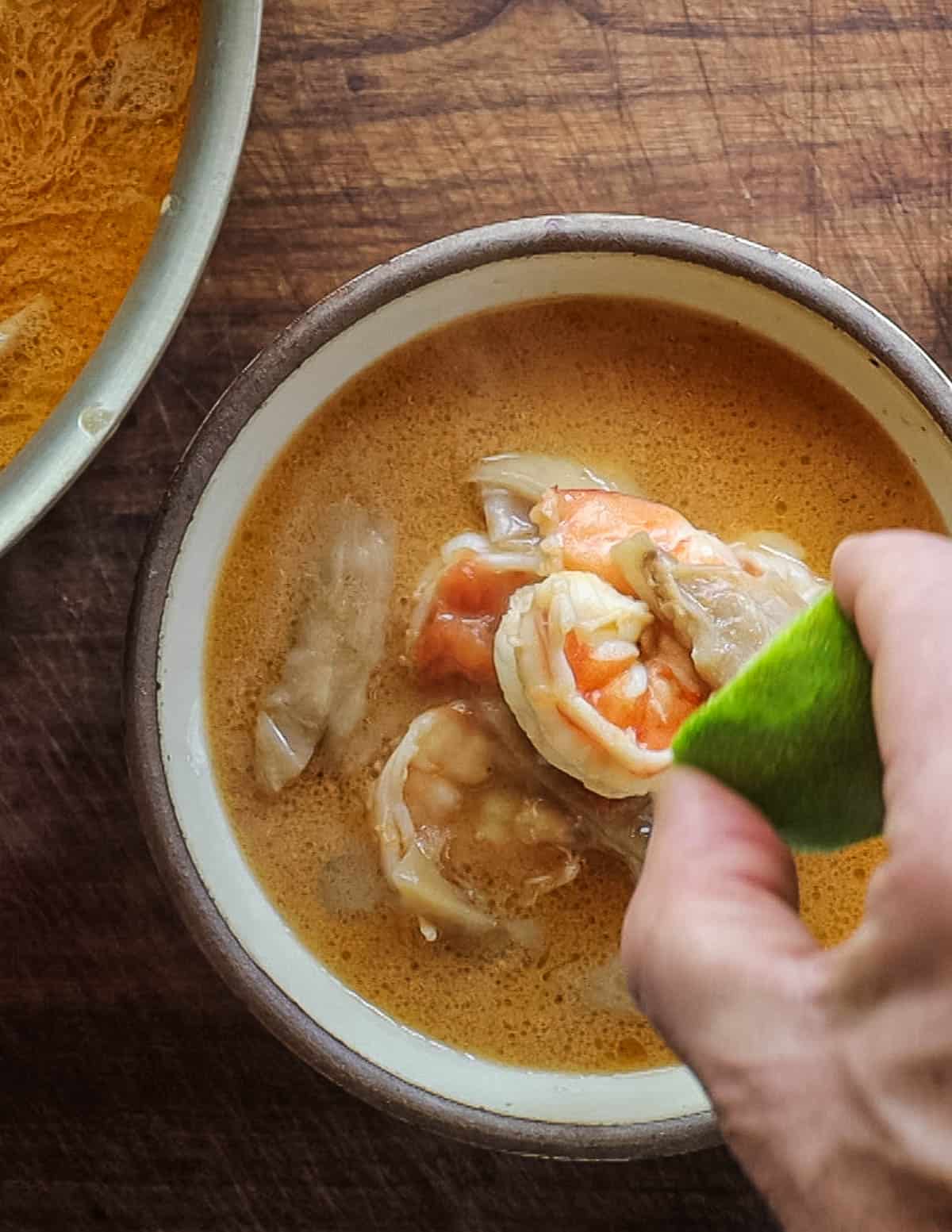 Adding lime juice to a pot of Thai soup. 