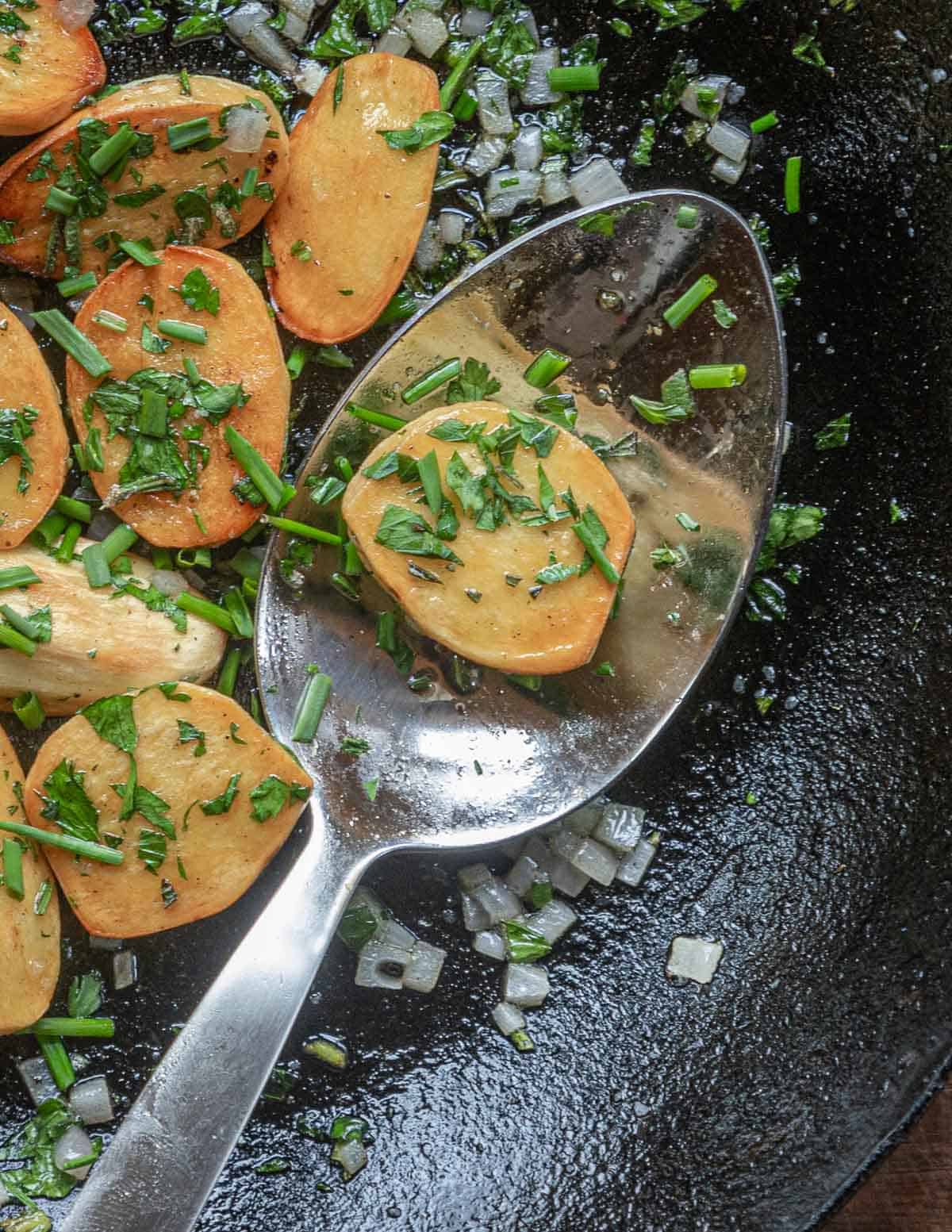 A pan of fried katniss potatoes with shallots and herbs.