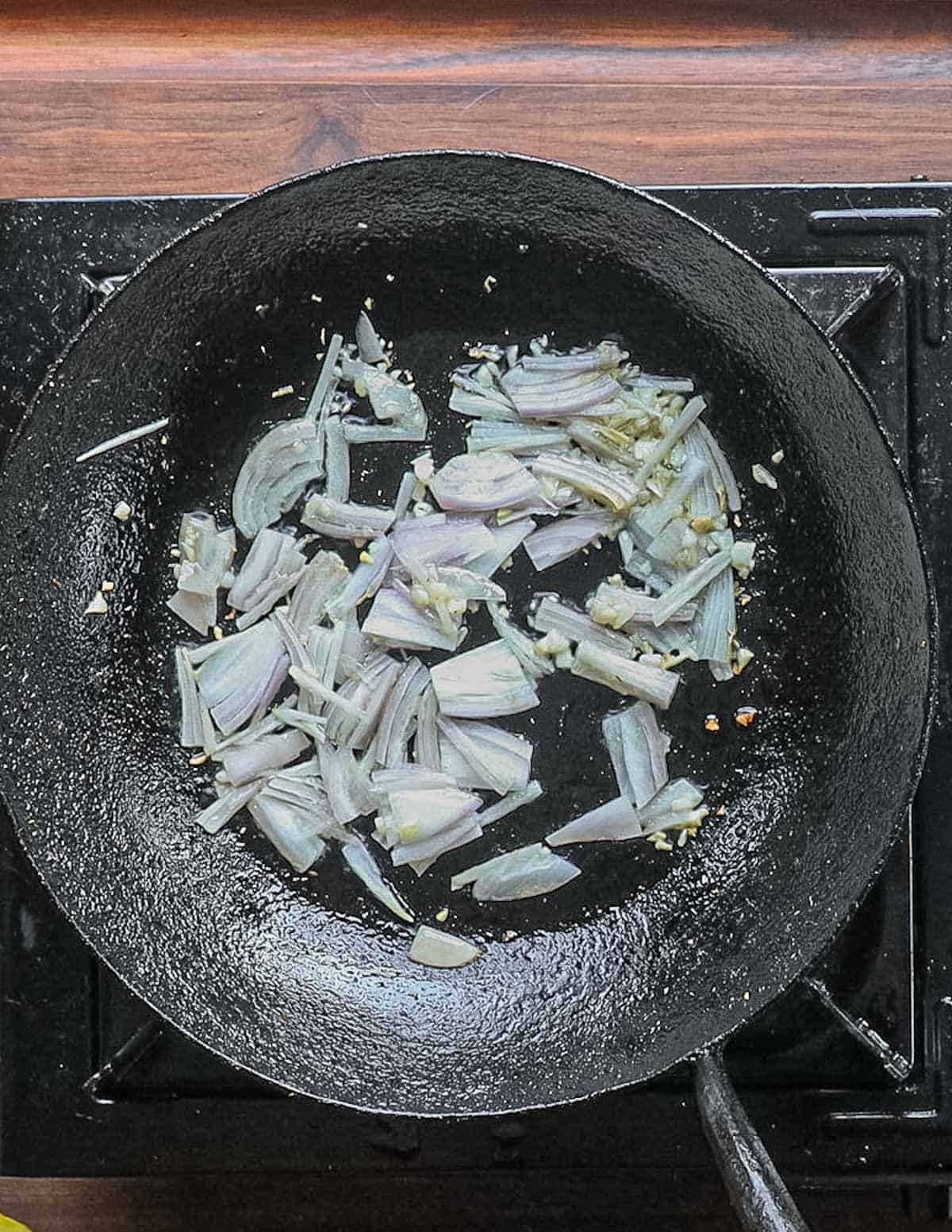 Cooking garlic and sliced shallot in a pan. 