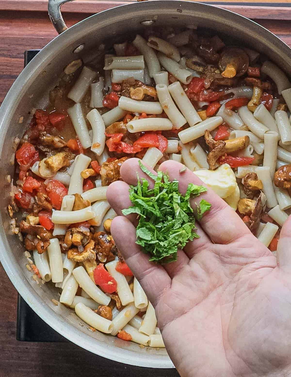 Adding fresh sliced mint leaves to a mushroom pasta. 