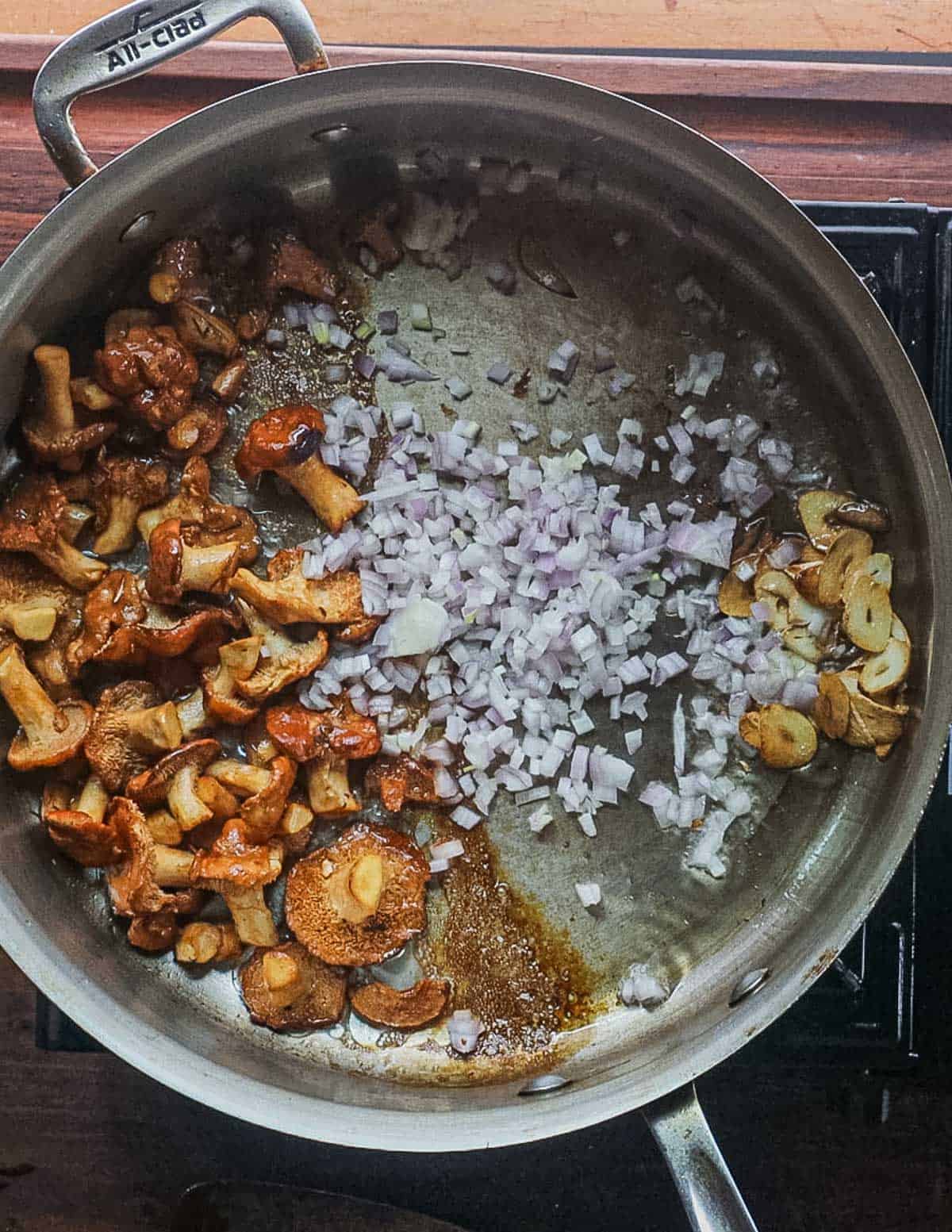 Adding shallots to a pan of cooking mushrooms and garlic. 