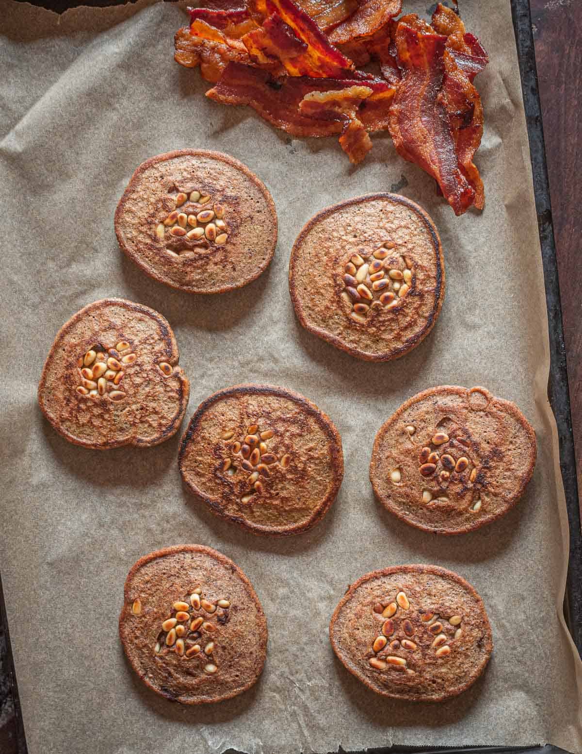 A baking sheet with brown acorn pancakes and bacon seed from above. 