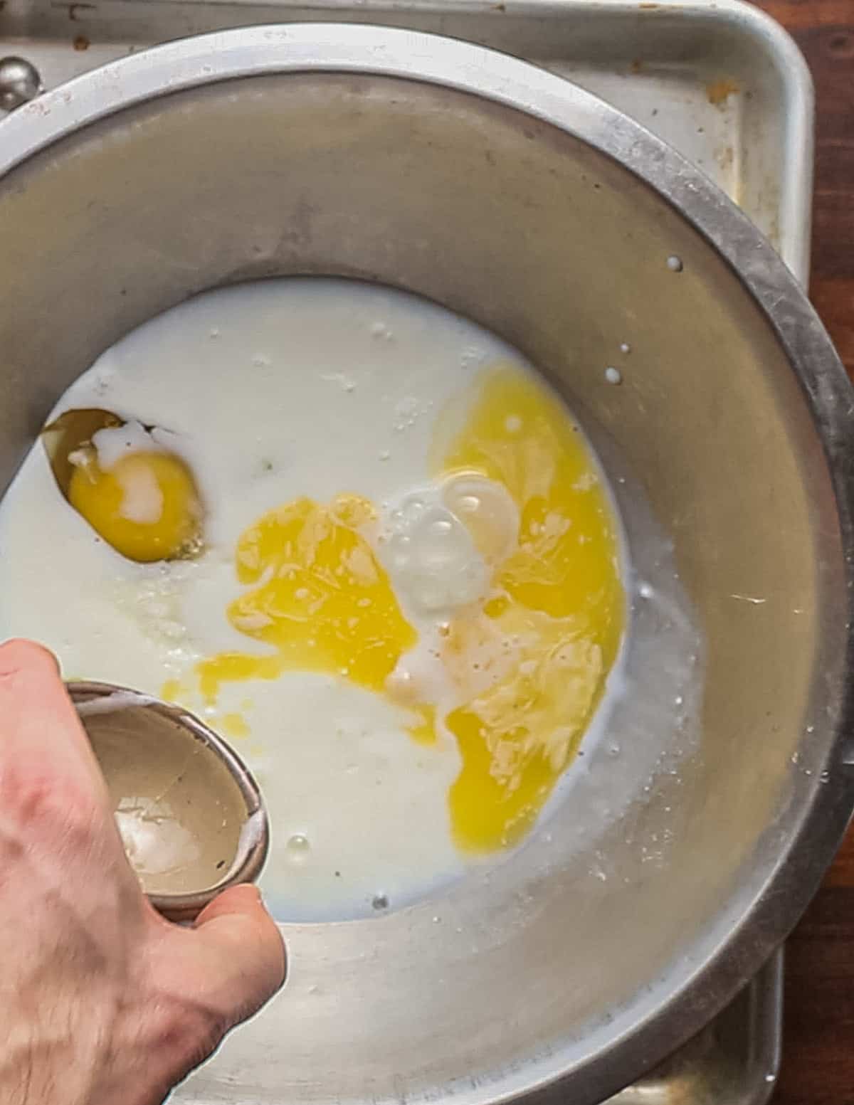 Adding melted butter to a bowl of buttermilk and eggs. 