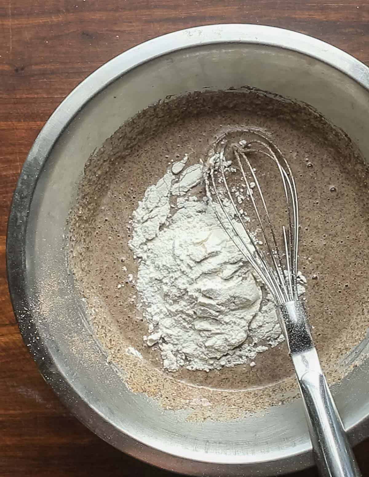 Adding wheat flour to a bowl of acorn pancake mixture. 