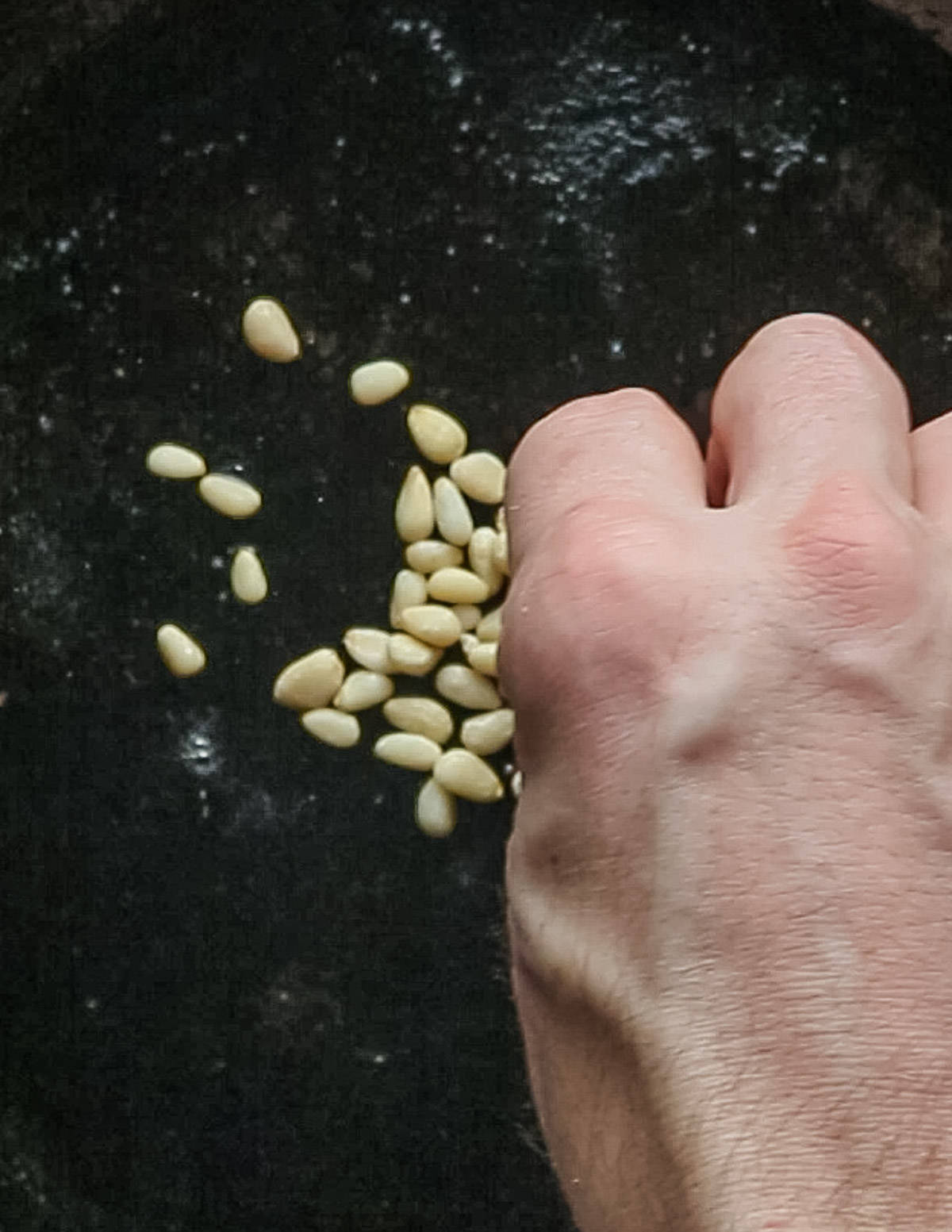 Putting pine nuts in a pan. 