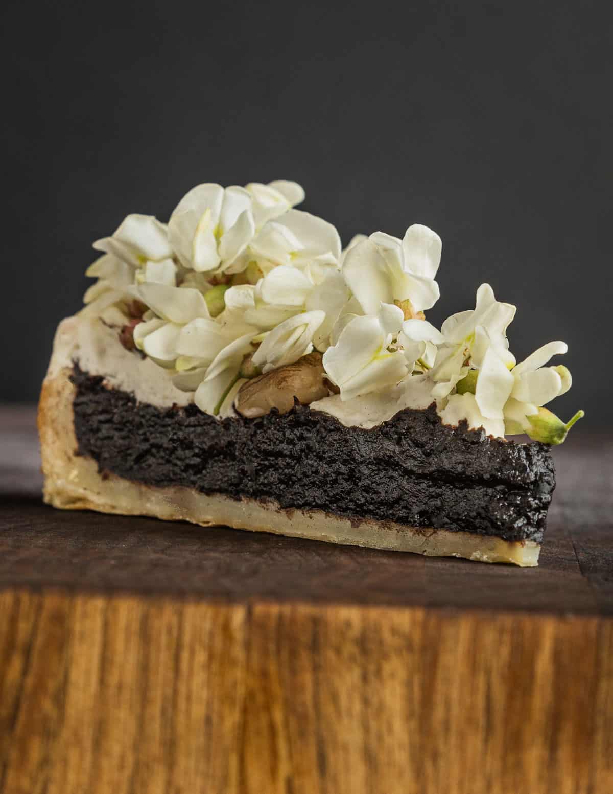 A slice of nannyberry torte dessert covered with whipped cream, butternuts, candied angelica and black locust flowers. 