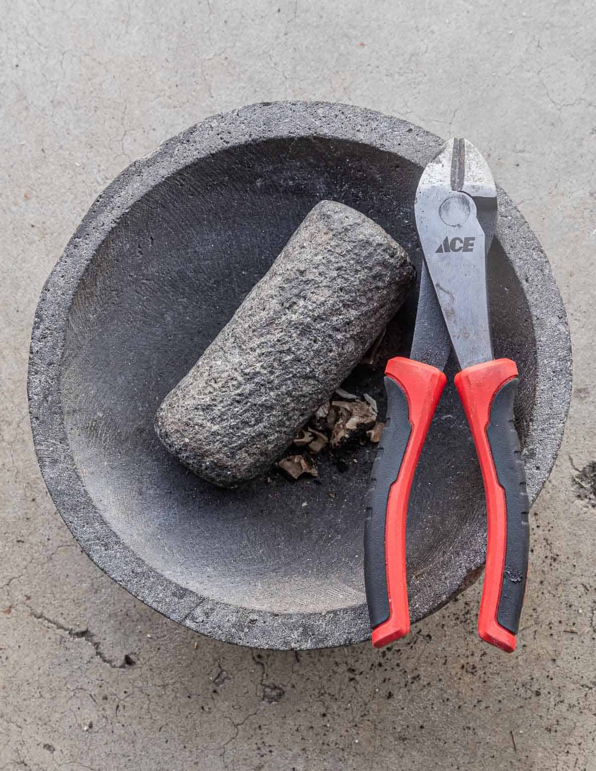 Using a molcajete and a snips to crack black walnuts. 