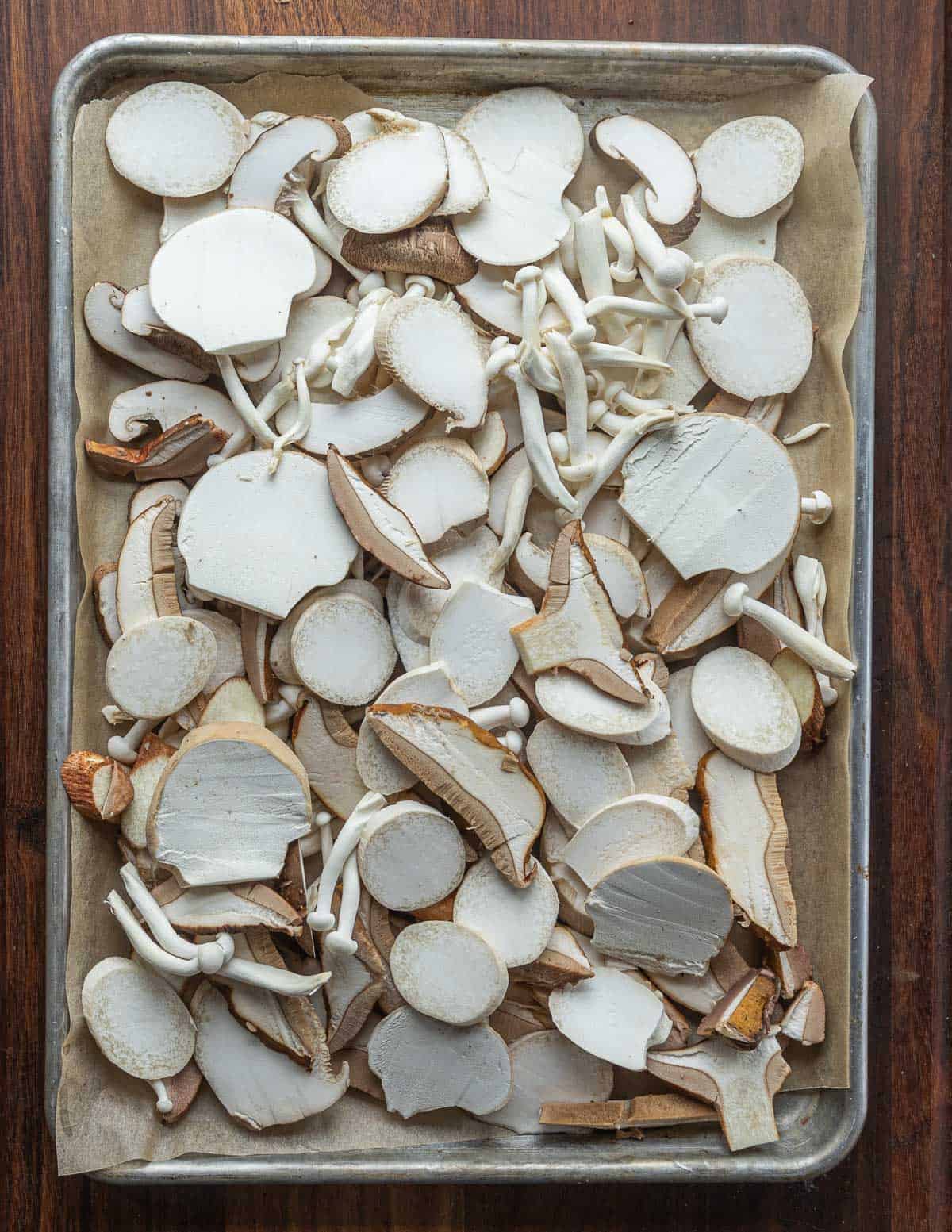 Sliced oyster, puffball and porcini mushrooms on a tray ready to be baked. 