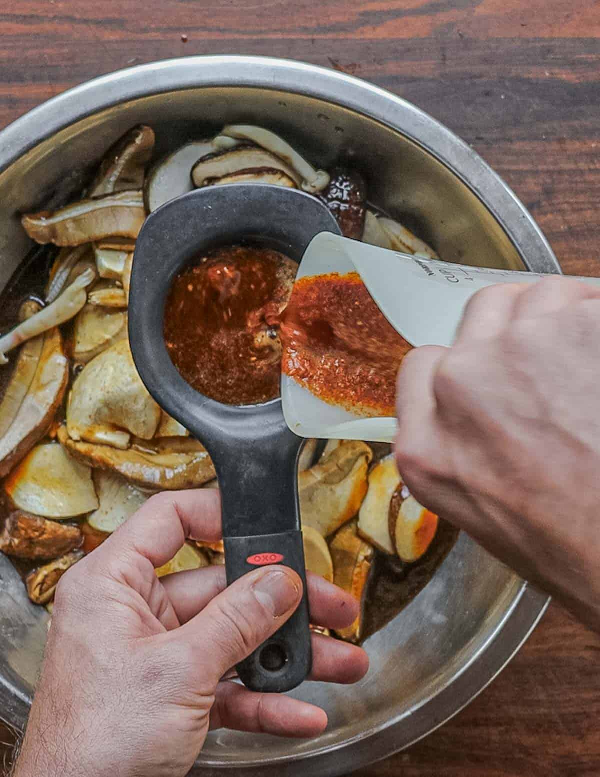 Straining jerky marinade and pouring it over mushrooms. 