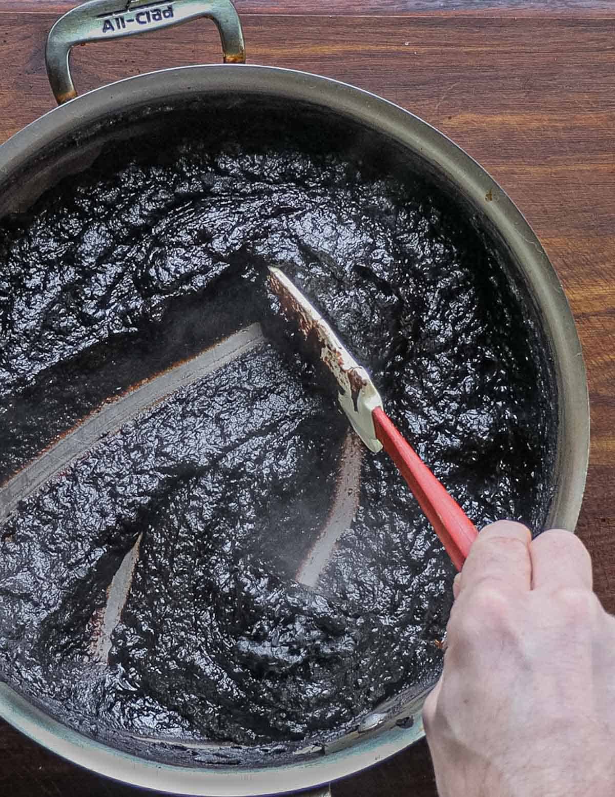 Pushing a spatula through a pan of baked nannyberry butter. 