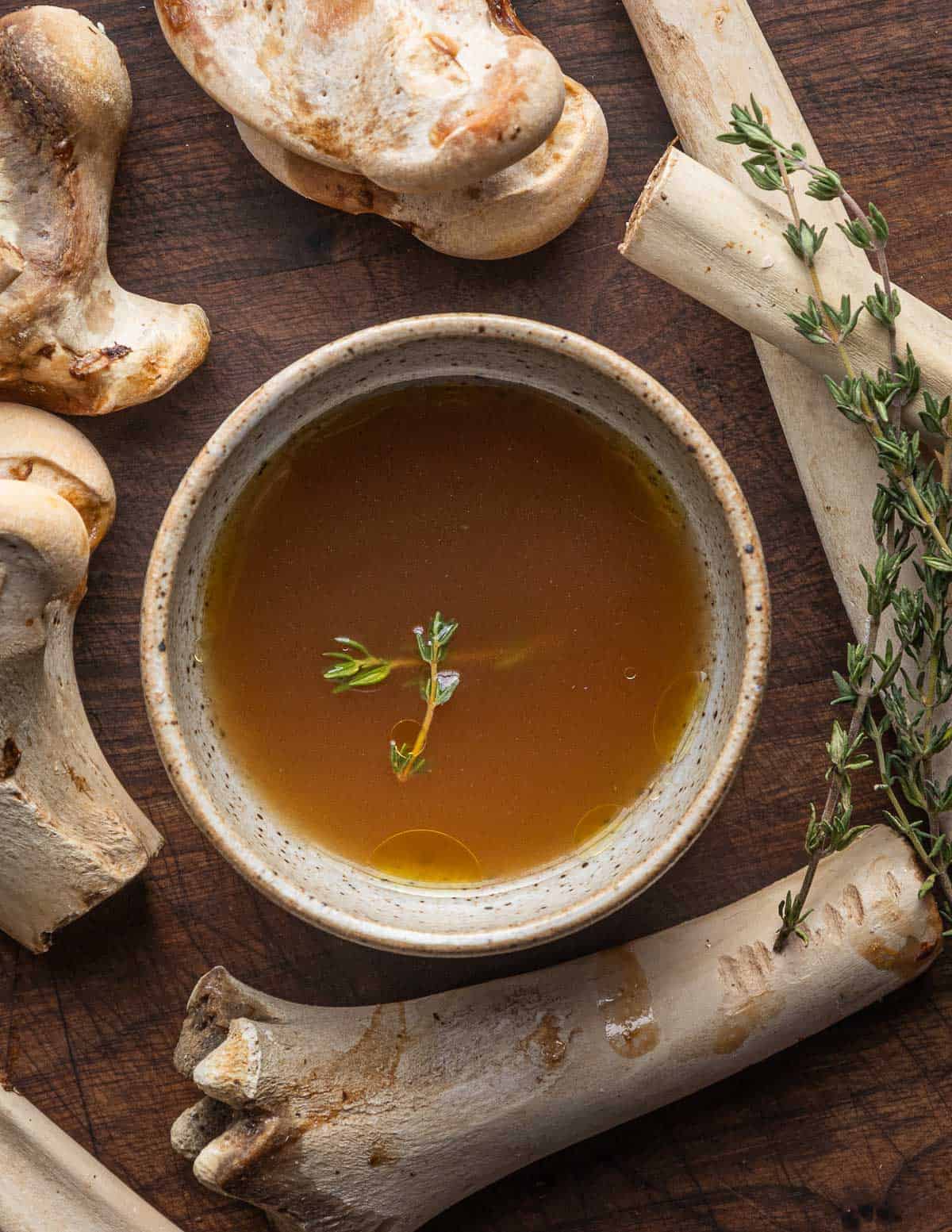 A cup of smoked deer bone broth surrounded by roasted venison bones.