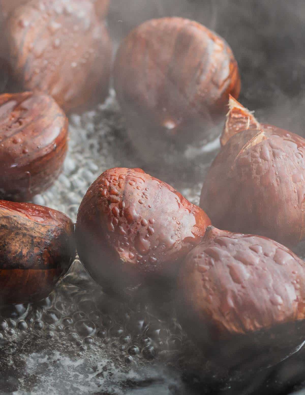 A close up image of chestnuts steaming in a cast iron pan.