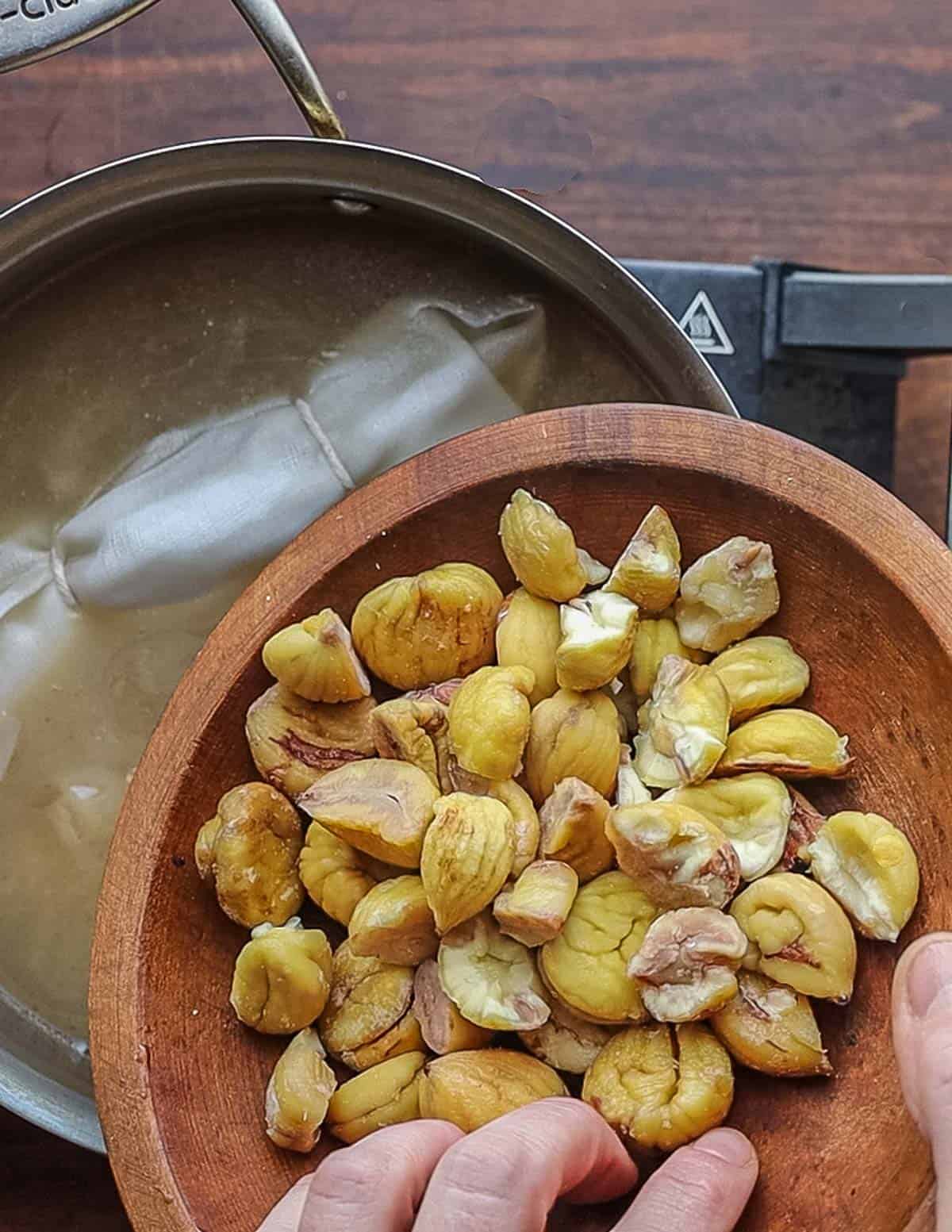 Adding cooked chestnuts and a bouquet of herbs to a pot of chicken stock and cooked onions.