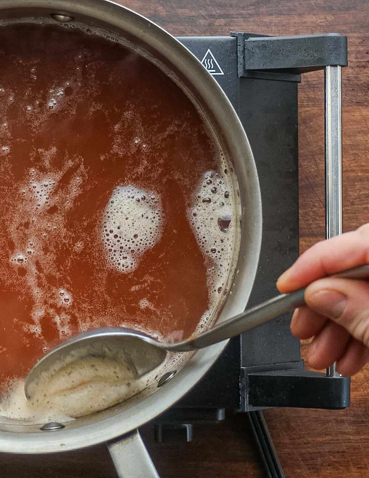 Skimming impurities from rosehip syrup as it cooks. 