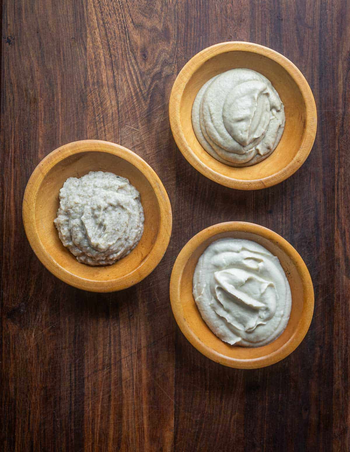 Three bowls filled with different jersusalem artichoke or sunchoke purees: peeled, unpeeled, and made in a food processor. 