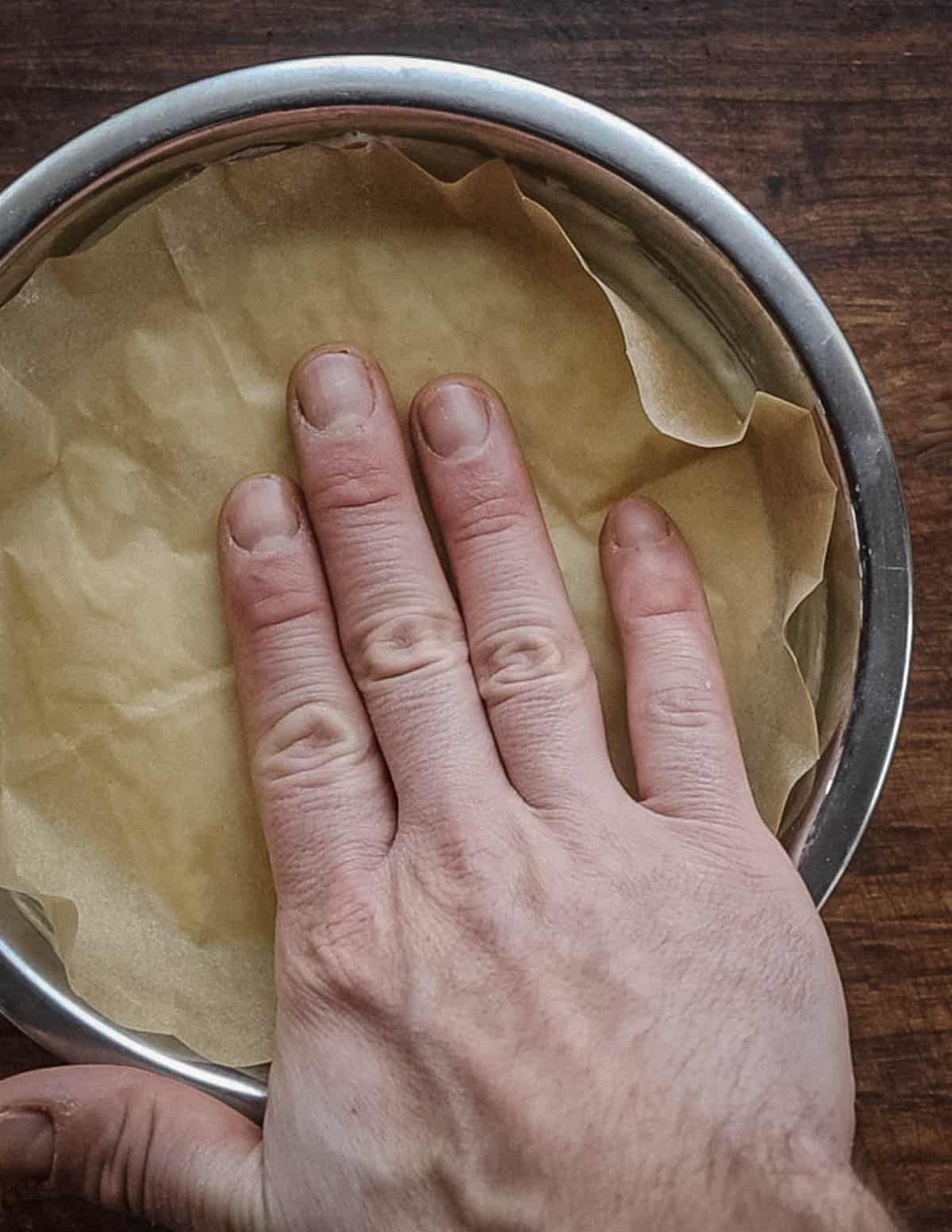 Putting parchment on a bowl of sunchoke puree to keep it warm in the oven. 