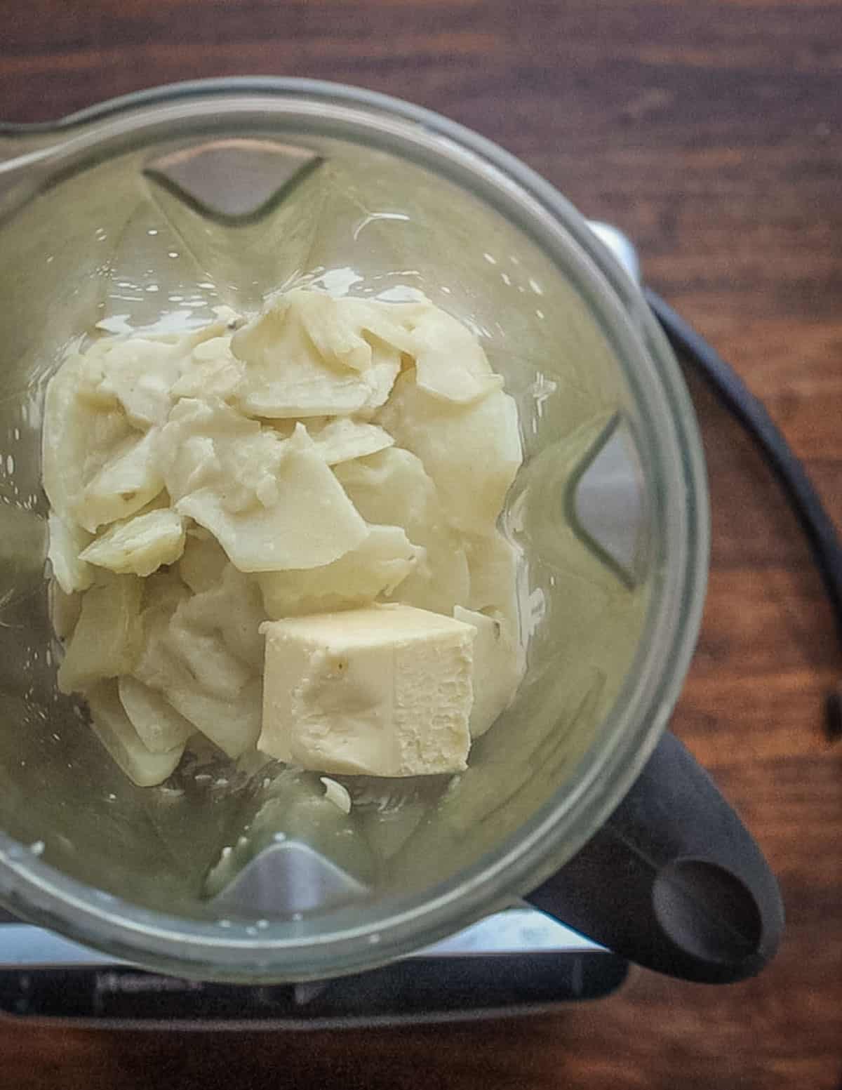 Putting cooked sunchokes in a VItamix blender with butter. 