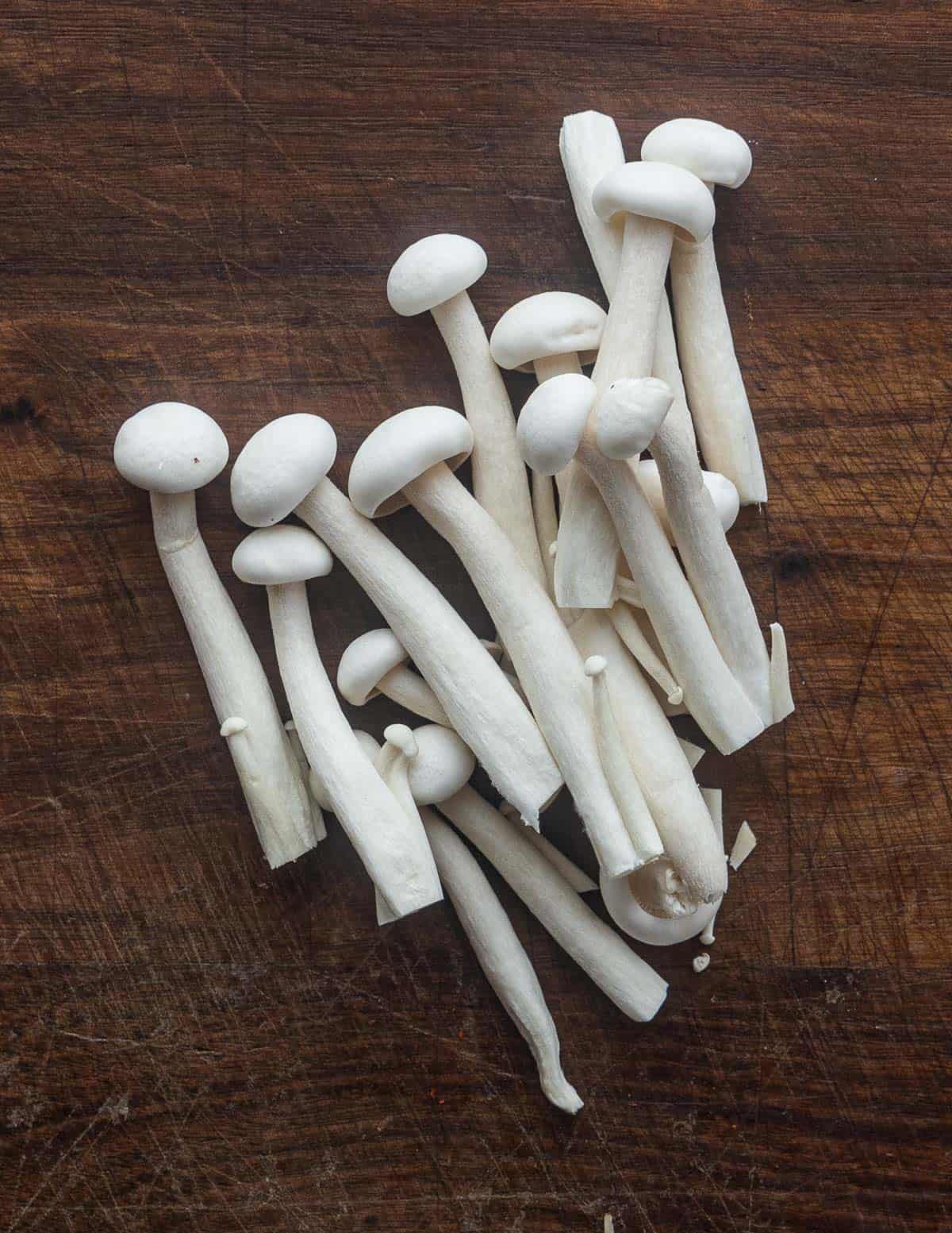 A pile of white beech mushrooms on a cutting board. 