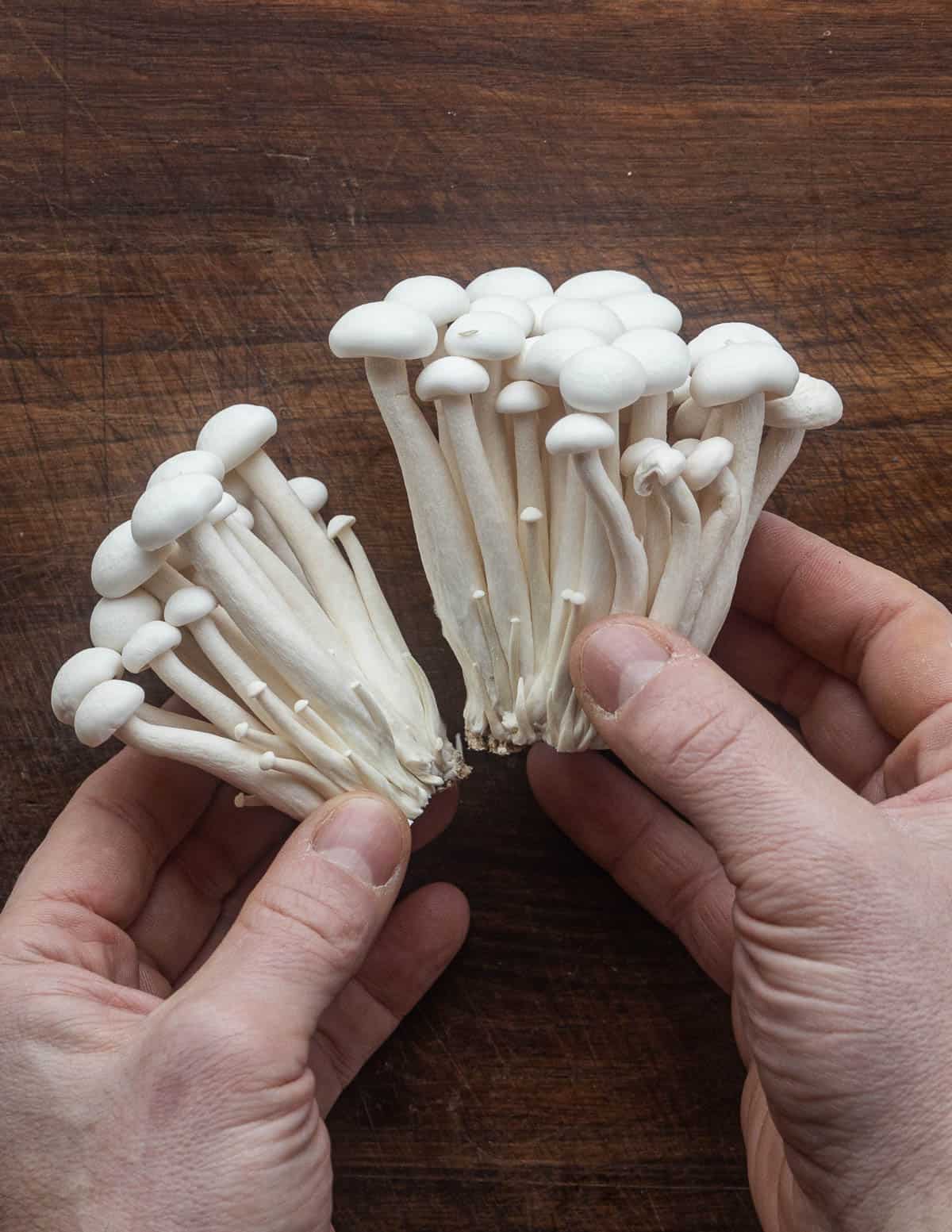 Breaking apart white beech mushrooms after removing from a clamshell. 