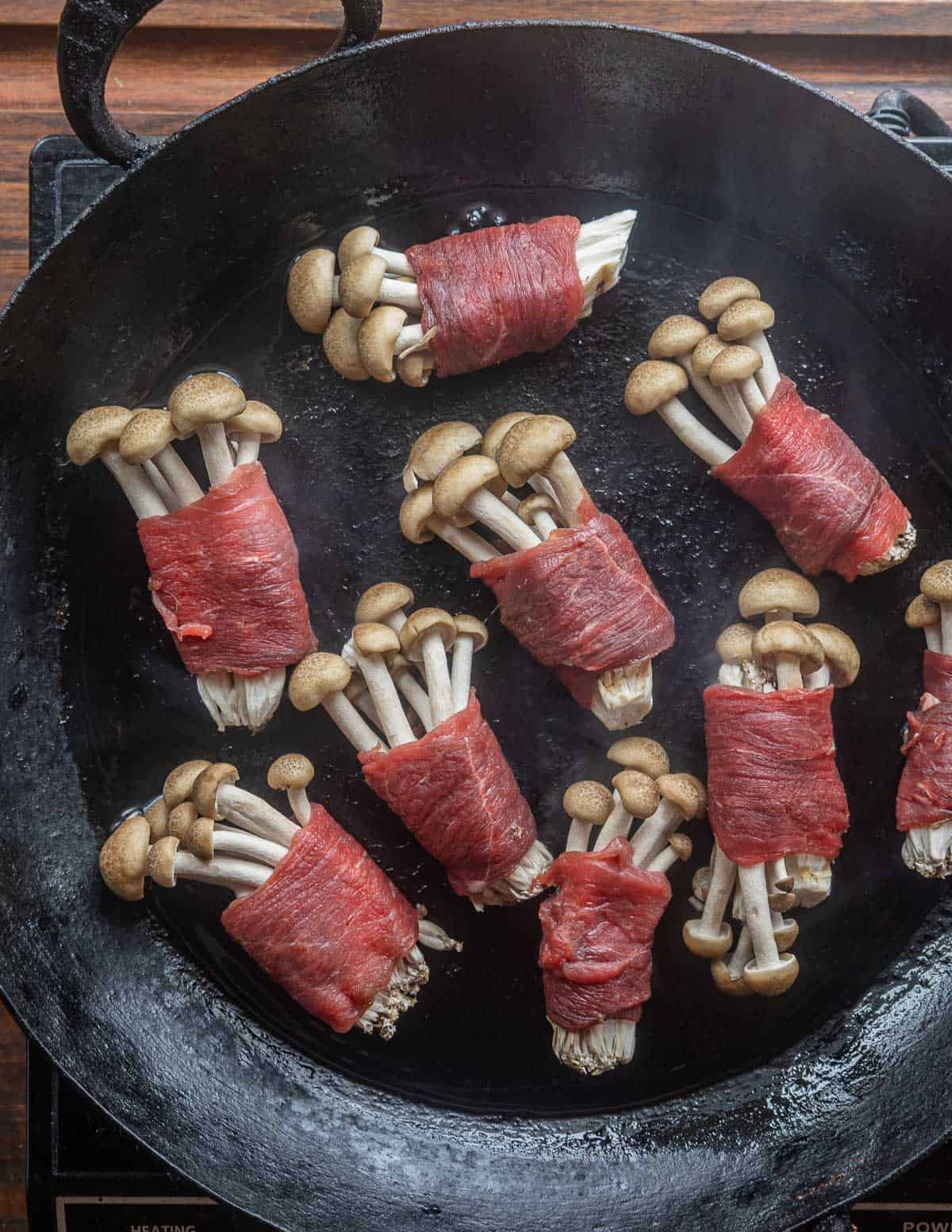 Cooking shimeji mushroom rolls in a carbon steel pan. 