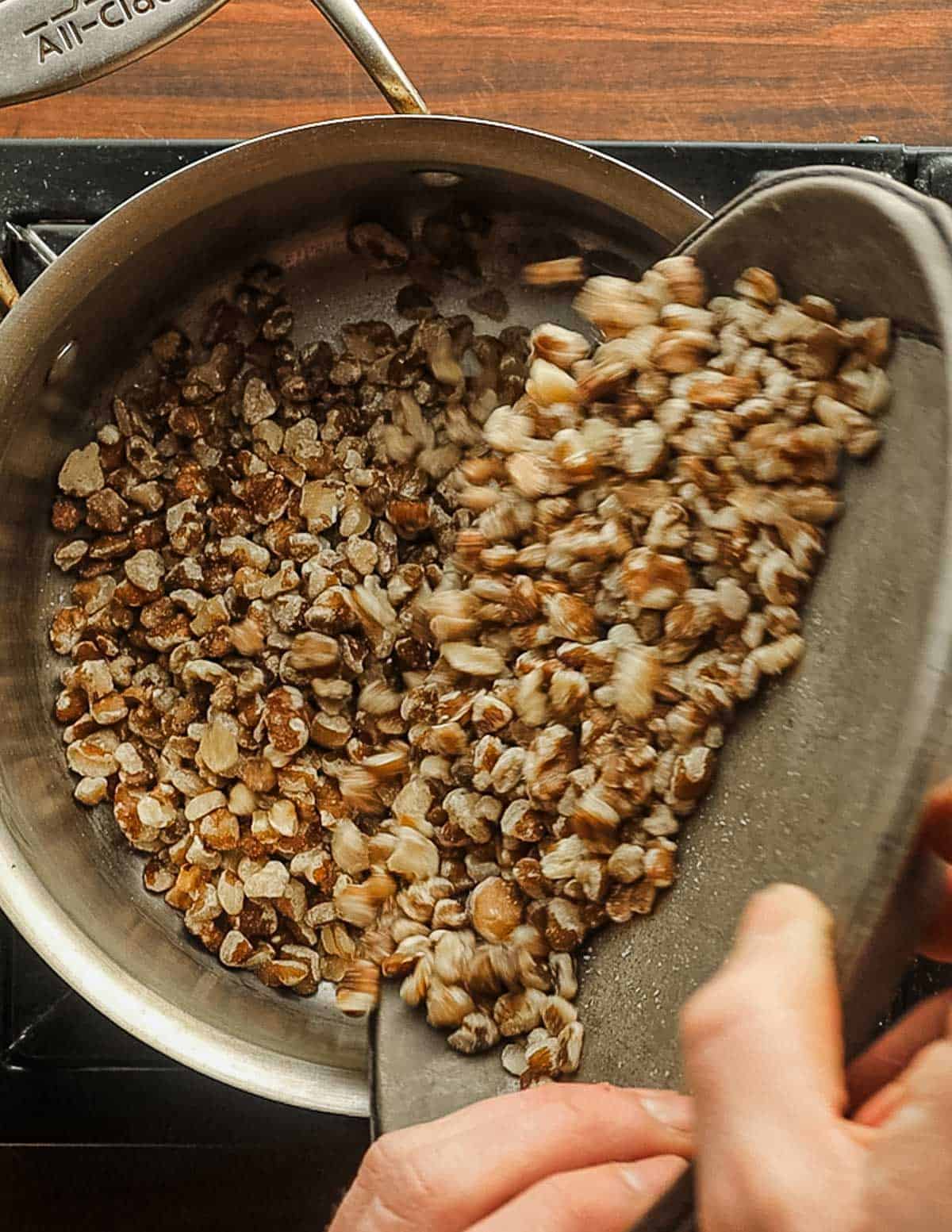 Adding black walnuts to a pot with sugar. 