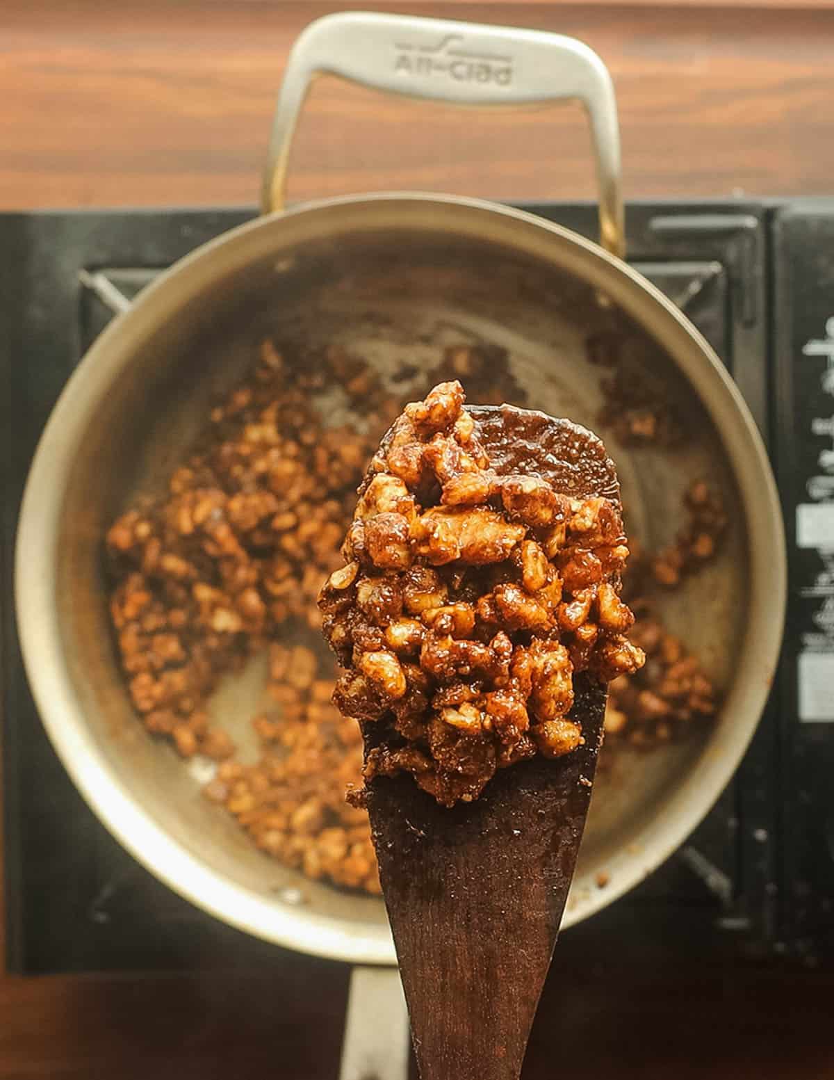 Candied golden brown black walnuts on a spatula. 