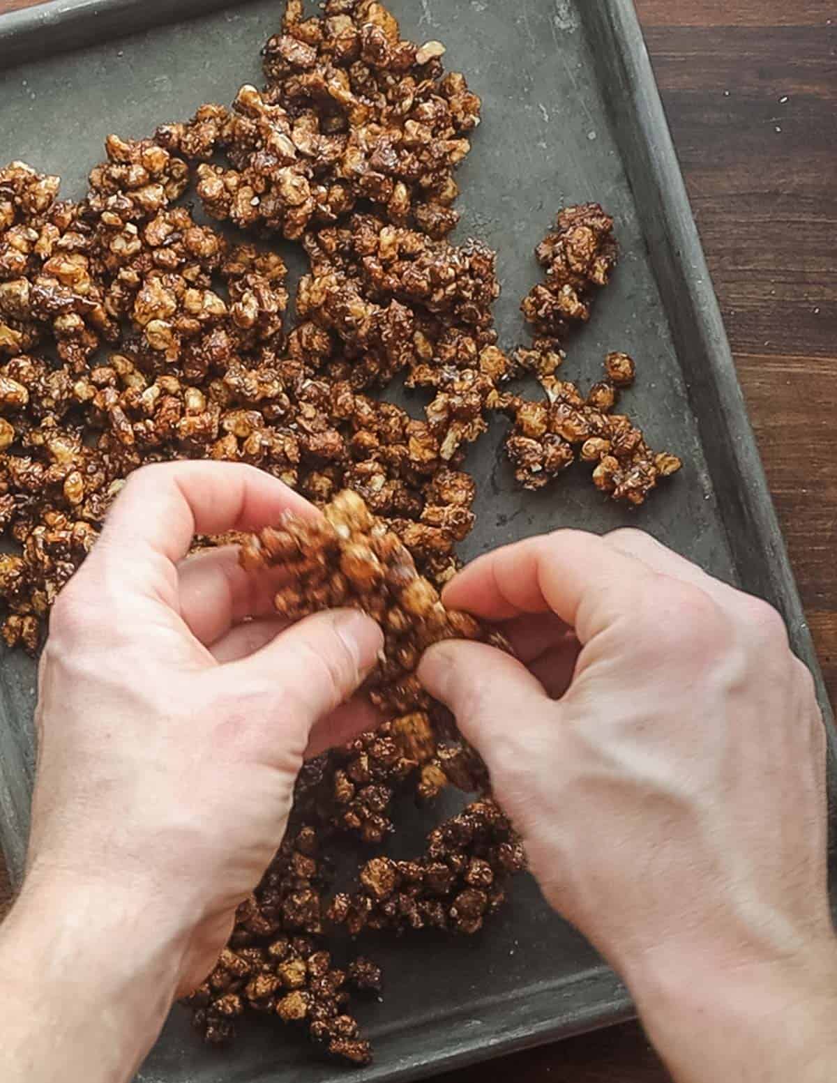 Breaking apart candied walnuts by hand after cooling. 