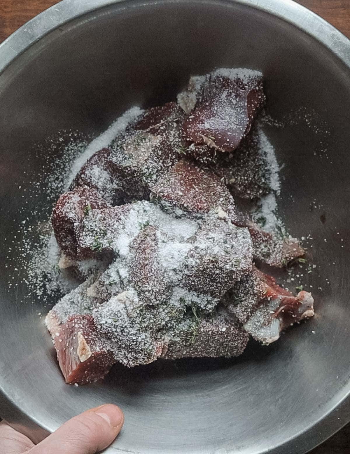Seasoning meat in a bowl with salt. 