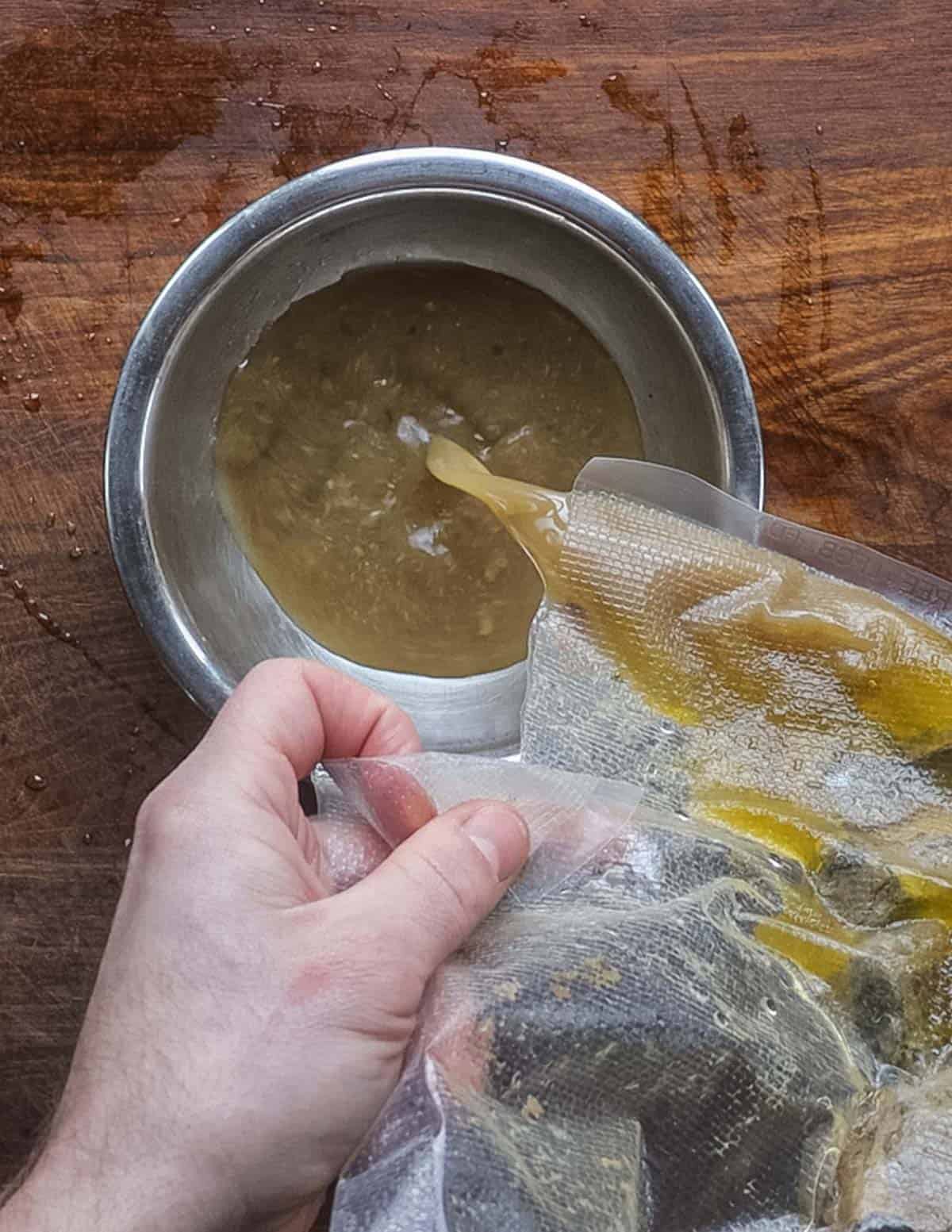 Pouring cooking liquid and fat from a vacuum sous vide bag into a bowl. 