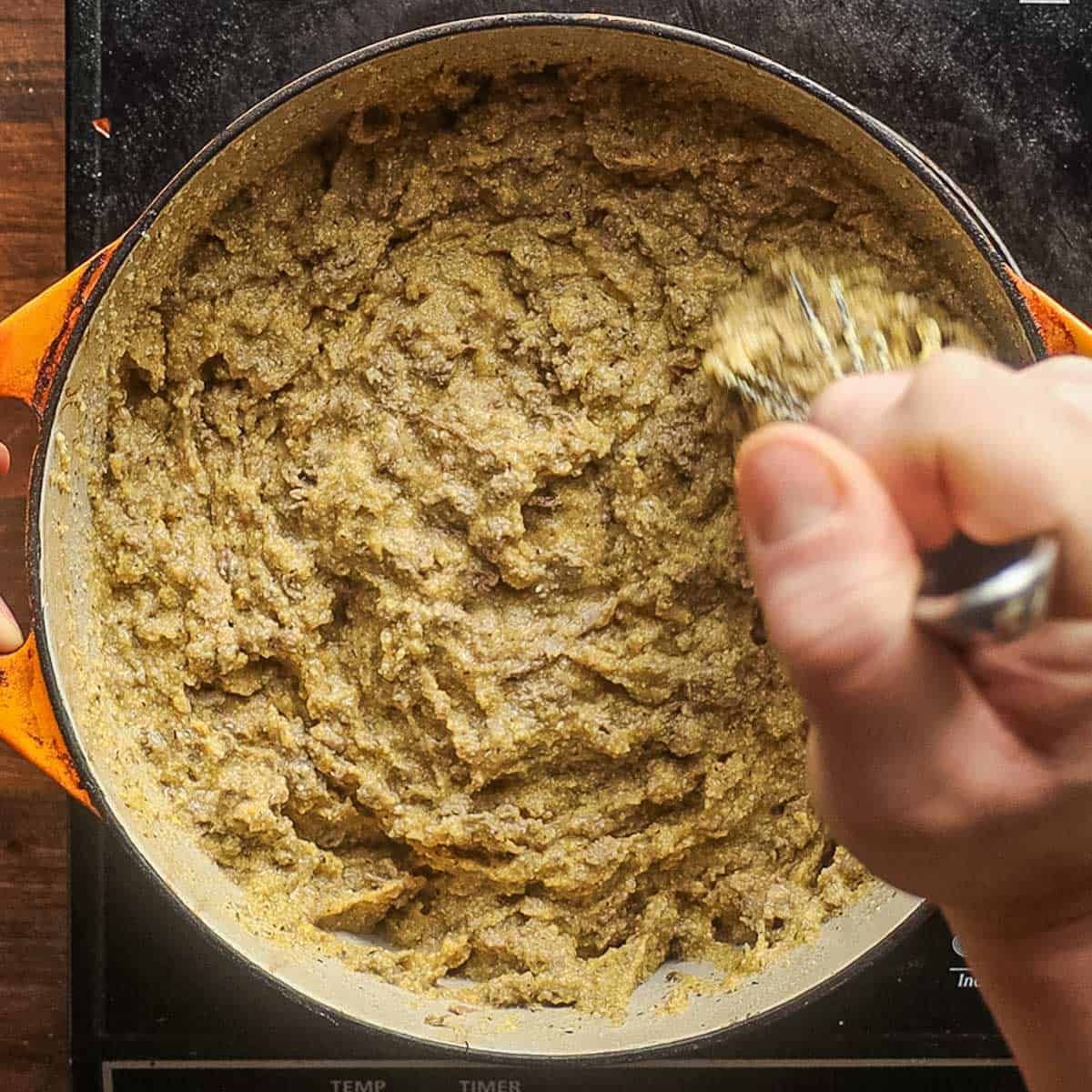 Mashing cornmeal together with cooked liver and meat with a whisk. 