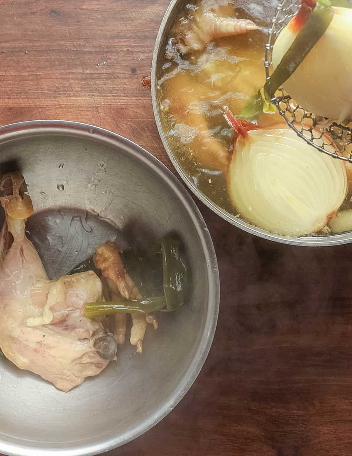 Straining finished ramen broth and reserving chicken legs for soup.