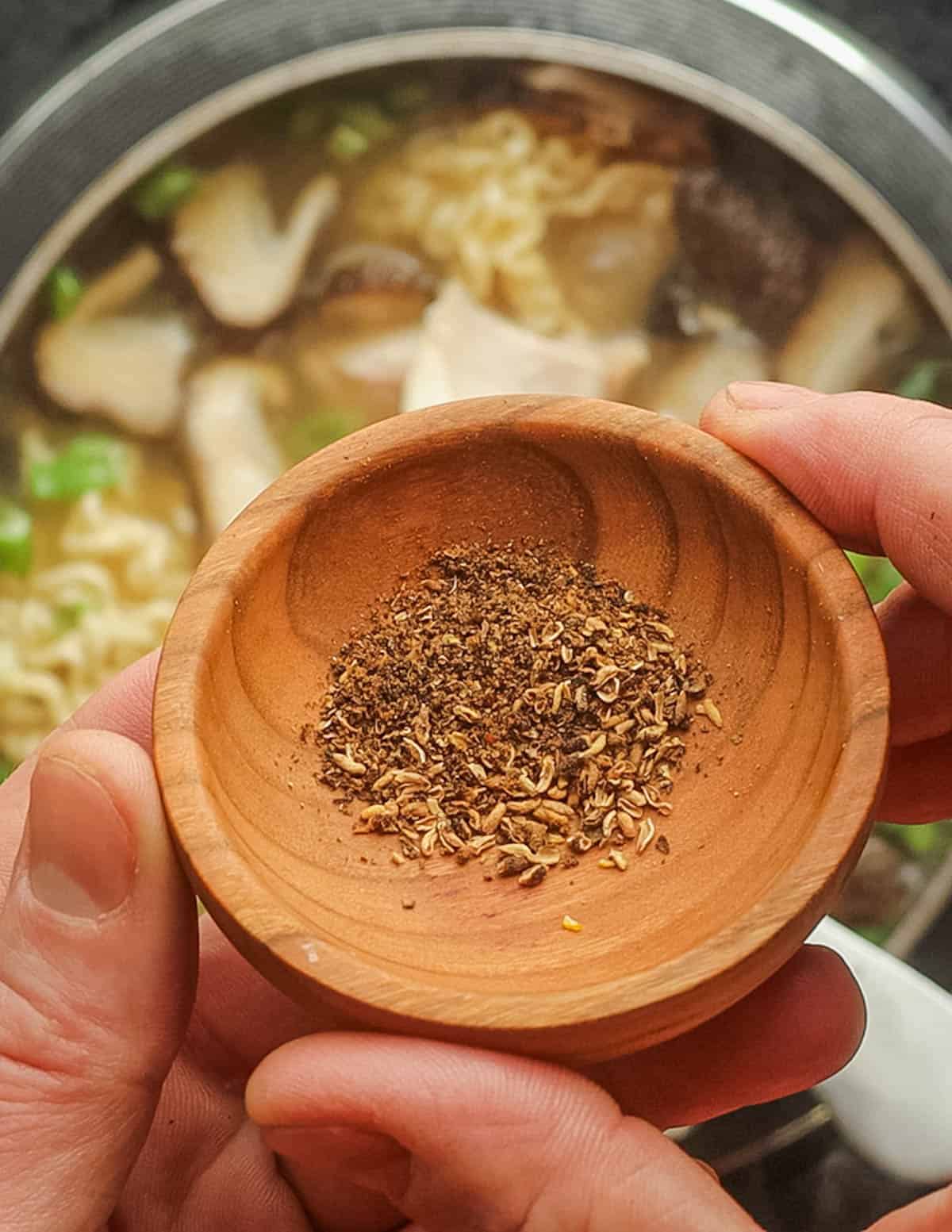 Adding ground Szechuan peppercorns or prickly ash to a pot of cooking ramen noodles.