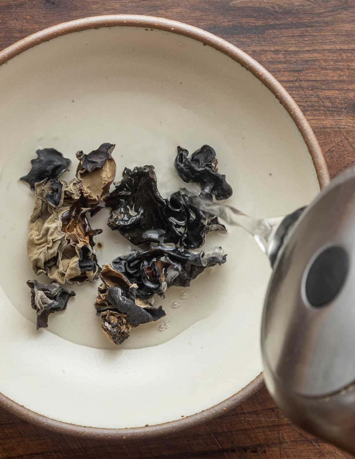 Pouring hot water over a bowl of  dried wood ear mushrooms. 