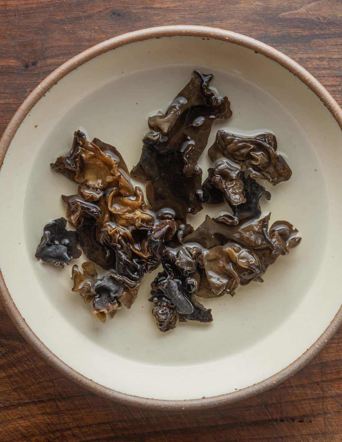 Dried mushrooms soaking in hot water in a bowl. 