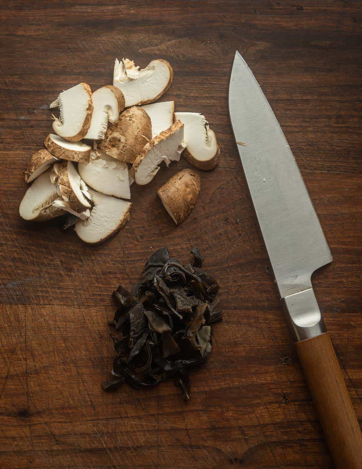 Sliced wood ear and shiitake mushrooms on a cutting board.