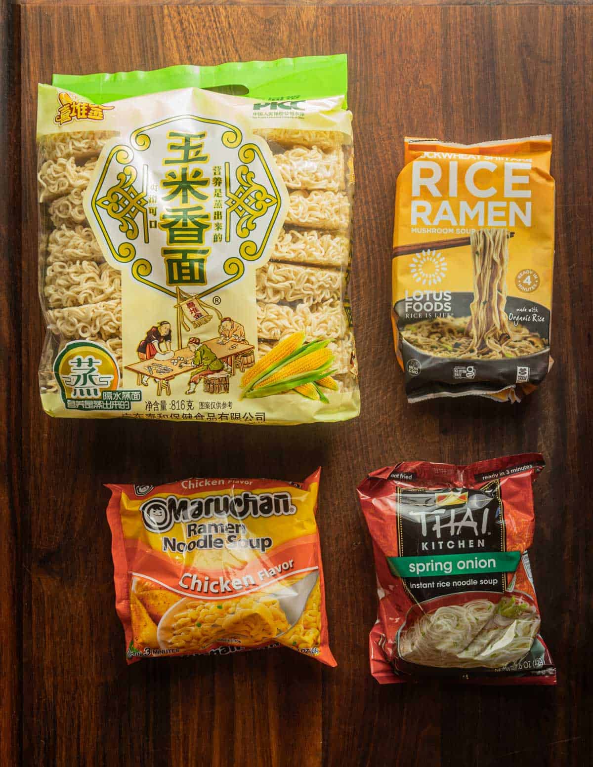 Different brands and types of ramen noodles in their packages laid out on a cutting board. 