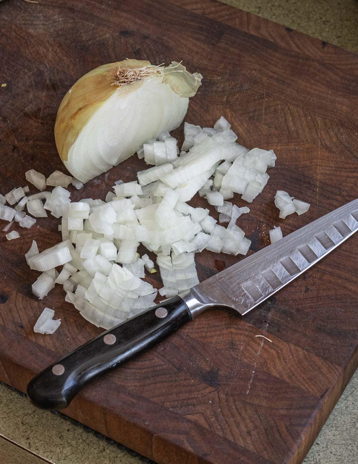 A yellow onion being cut into small dice for risotto. 