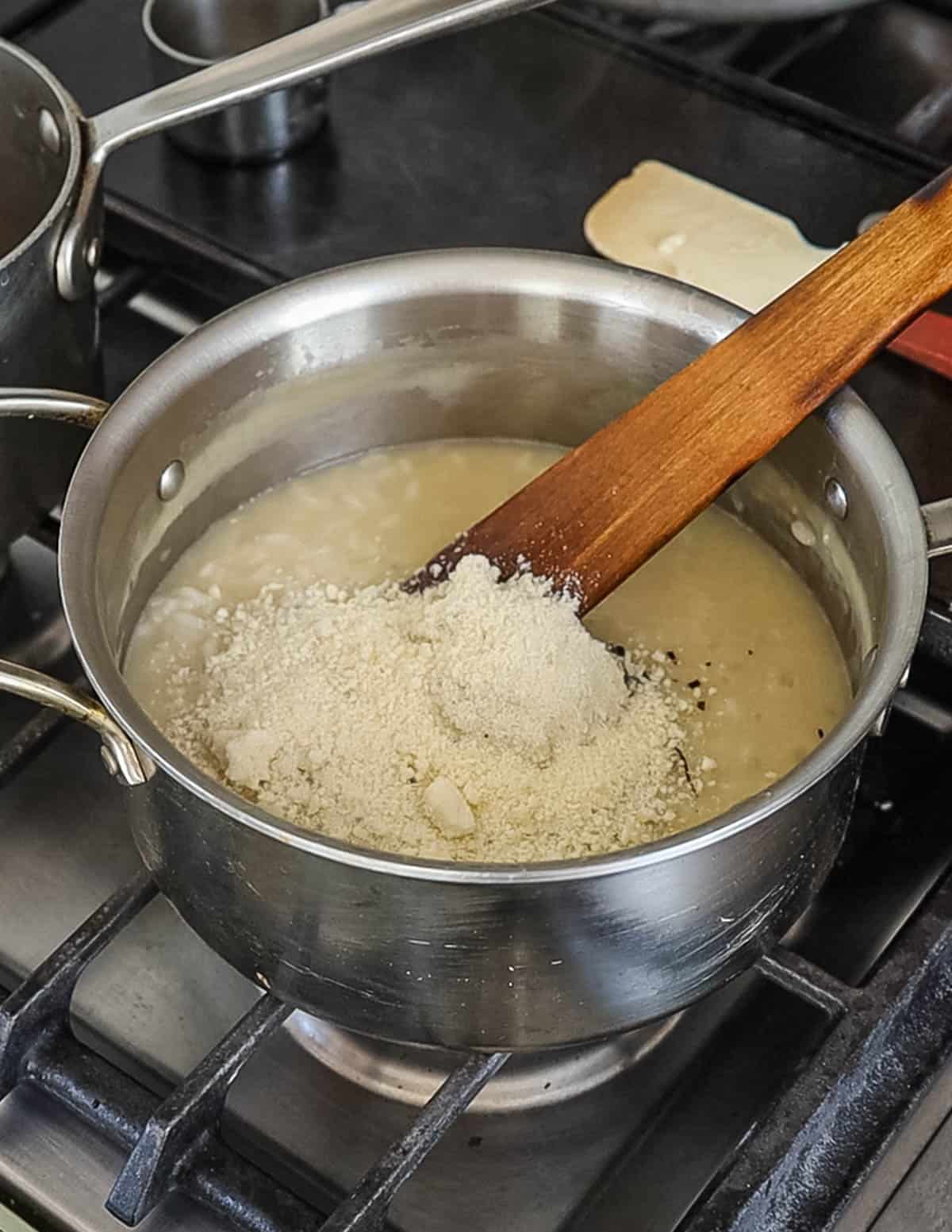 Adding parmesan cheese to a pot of risotto. 