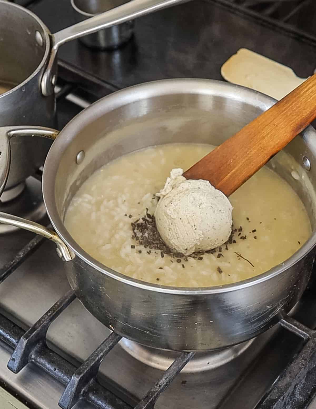 Adding truffle butter and minced truffle to risotto at the end of cooking. 