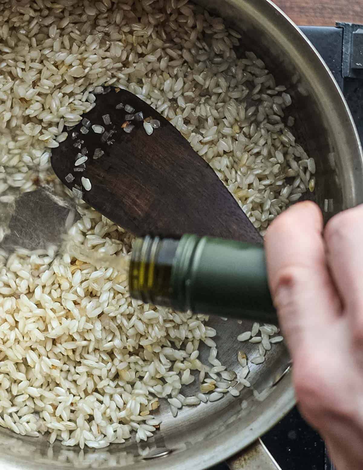 Adding wine to a pan of cooking risotto rice. 