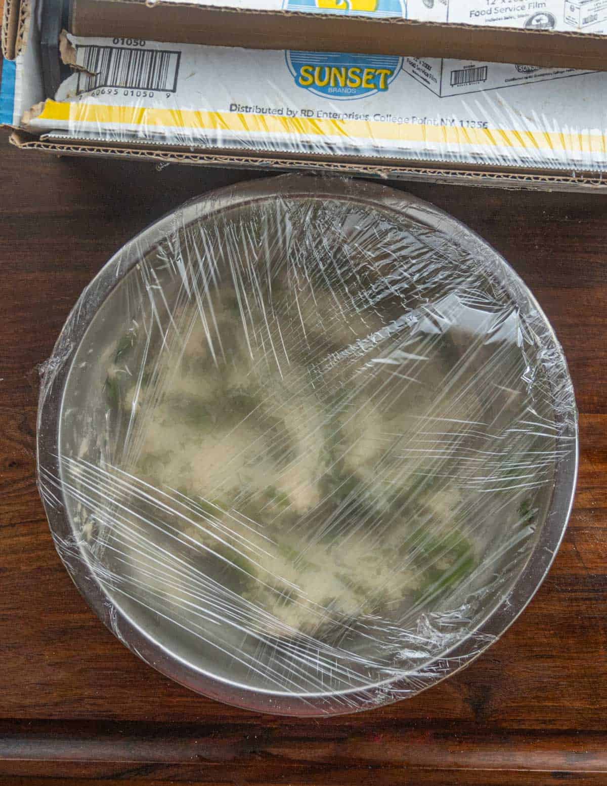 Wrapping a bowl of chipilin masa para tamales in cling film.