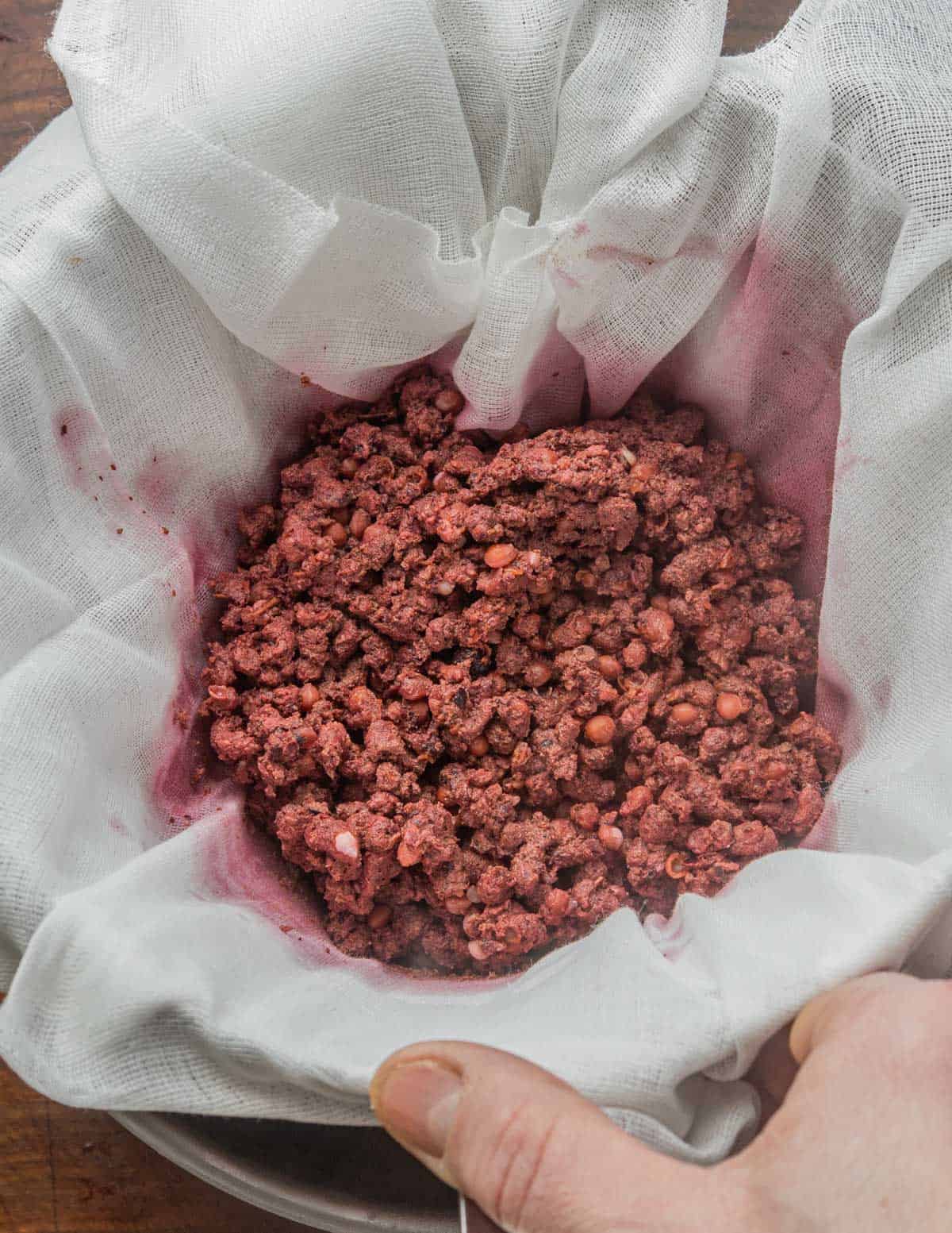 Straining cooked wild cherries through cheesecloth.